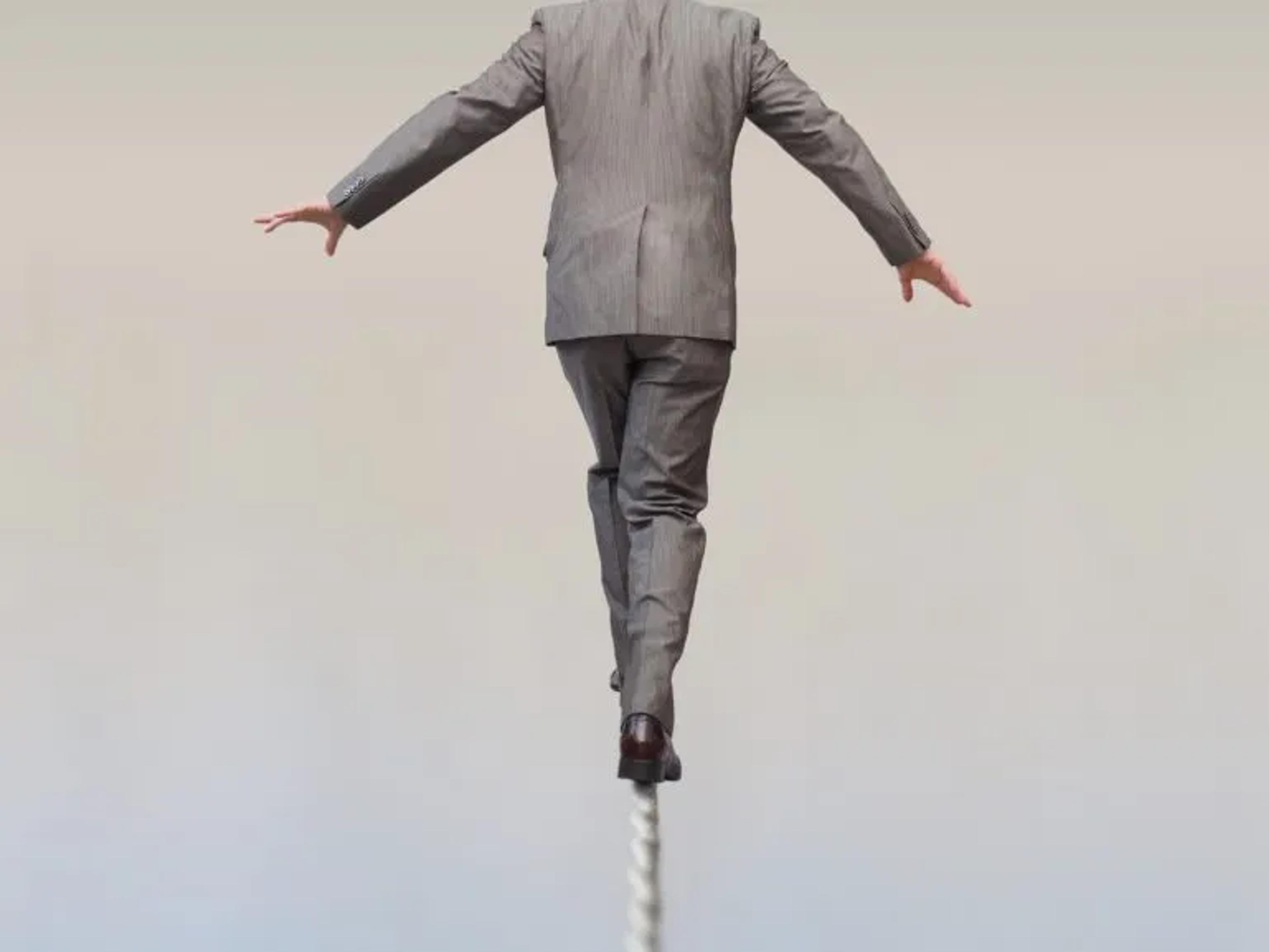 man in suite walking a risky, dangerous rope