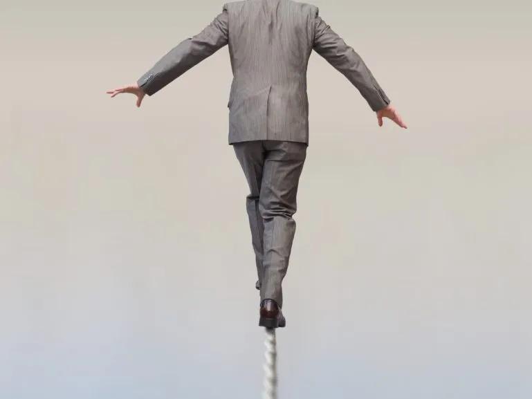 man in suite walking a risky, dangerous rope