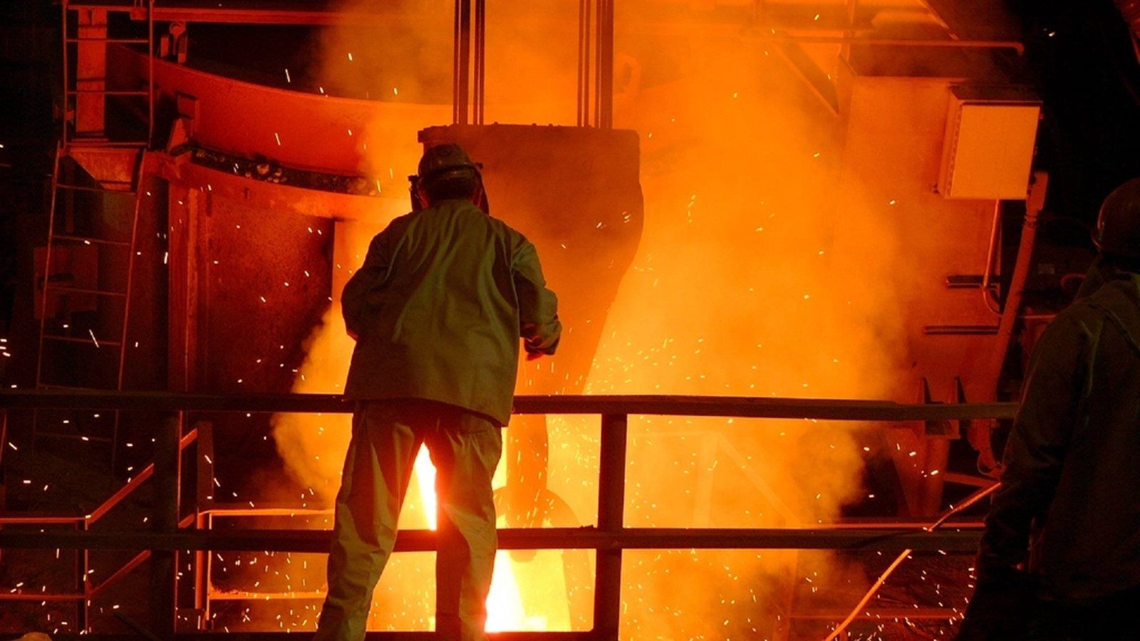 A worker at a steel furnace, sparks in the air