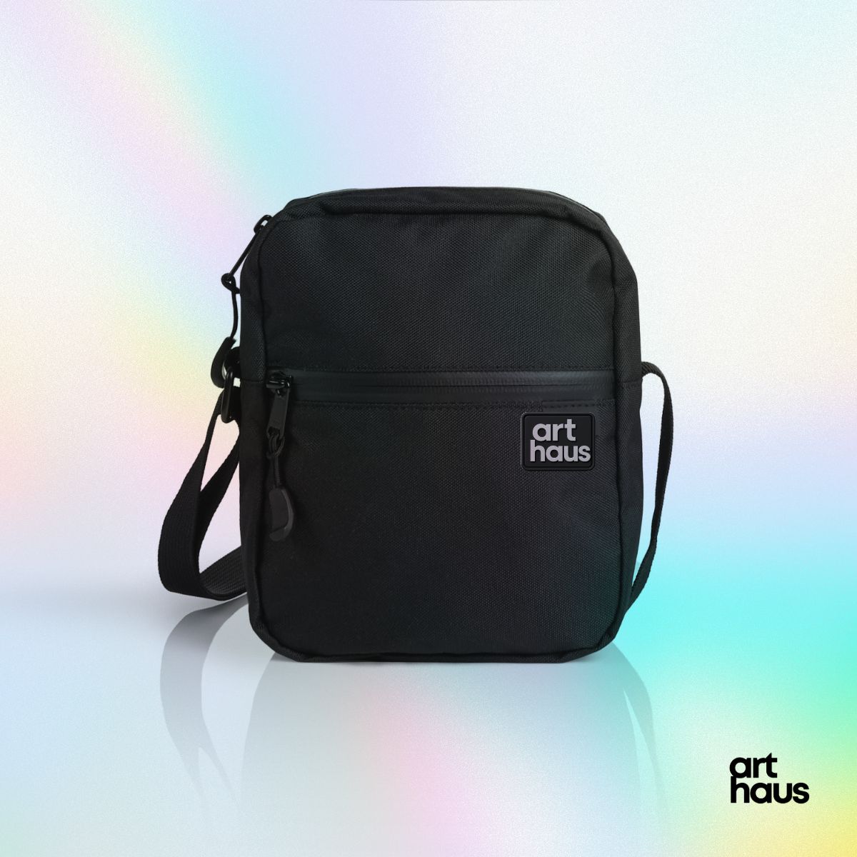 Black Art Haus crossbody bag with dimensional logo patch, photographed on a soft pastel gradient.