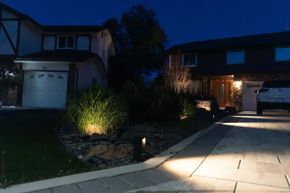 Lit walkway and garden in front of a house at dusk