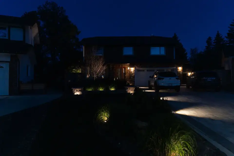Front yard with landscape lighting along garden beds at night