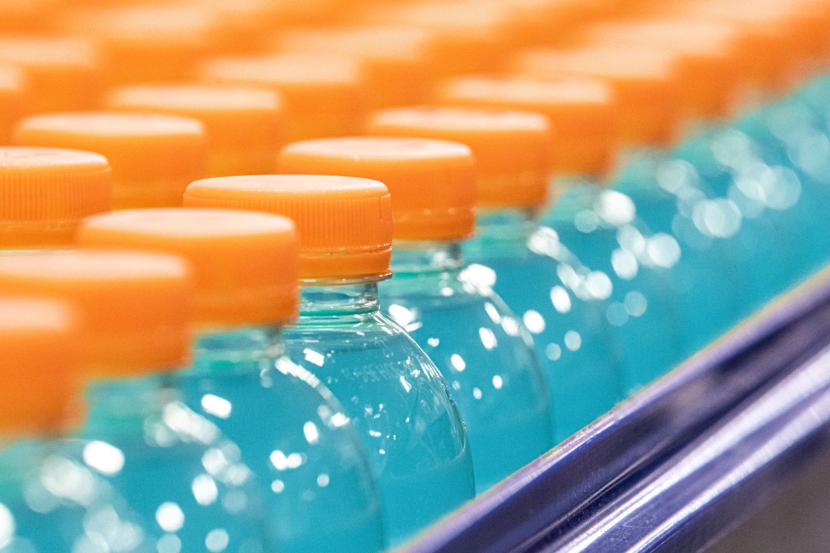 Rows of bottles that have an orange cap and contain a blue liquid.