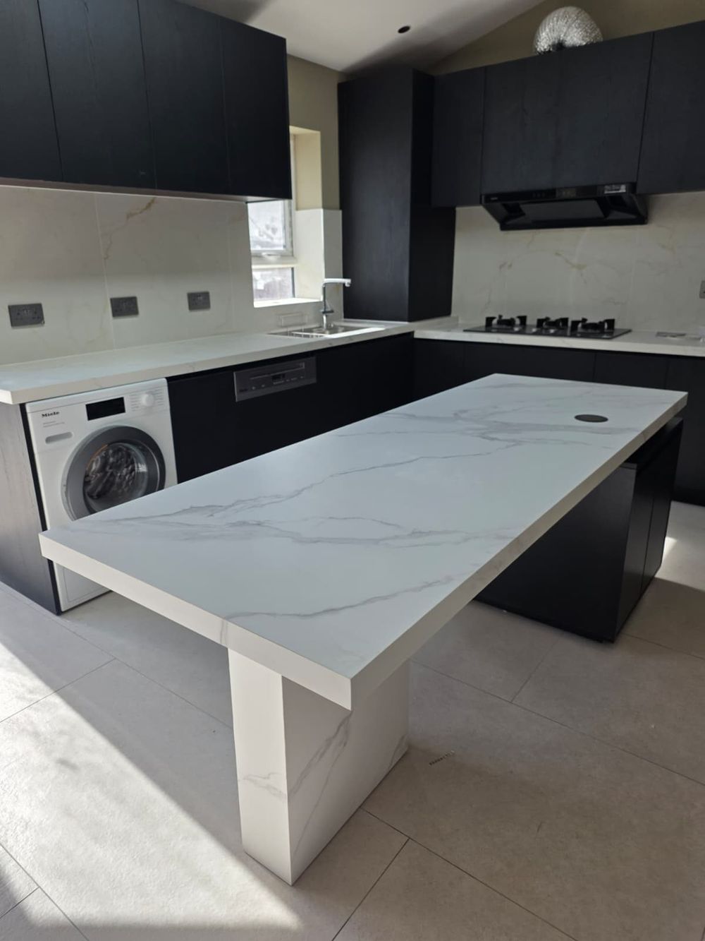 Marble kitchen island with dark cabinetry — Full House Renovation by TrustBuilt Projects