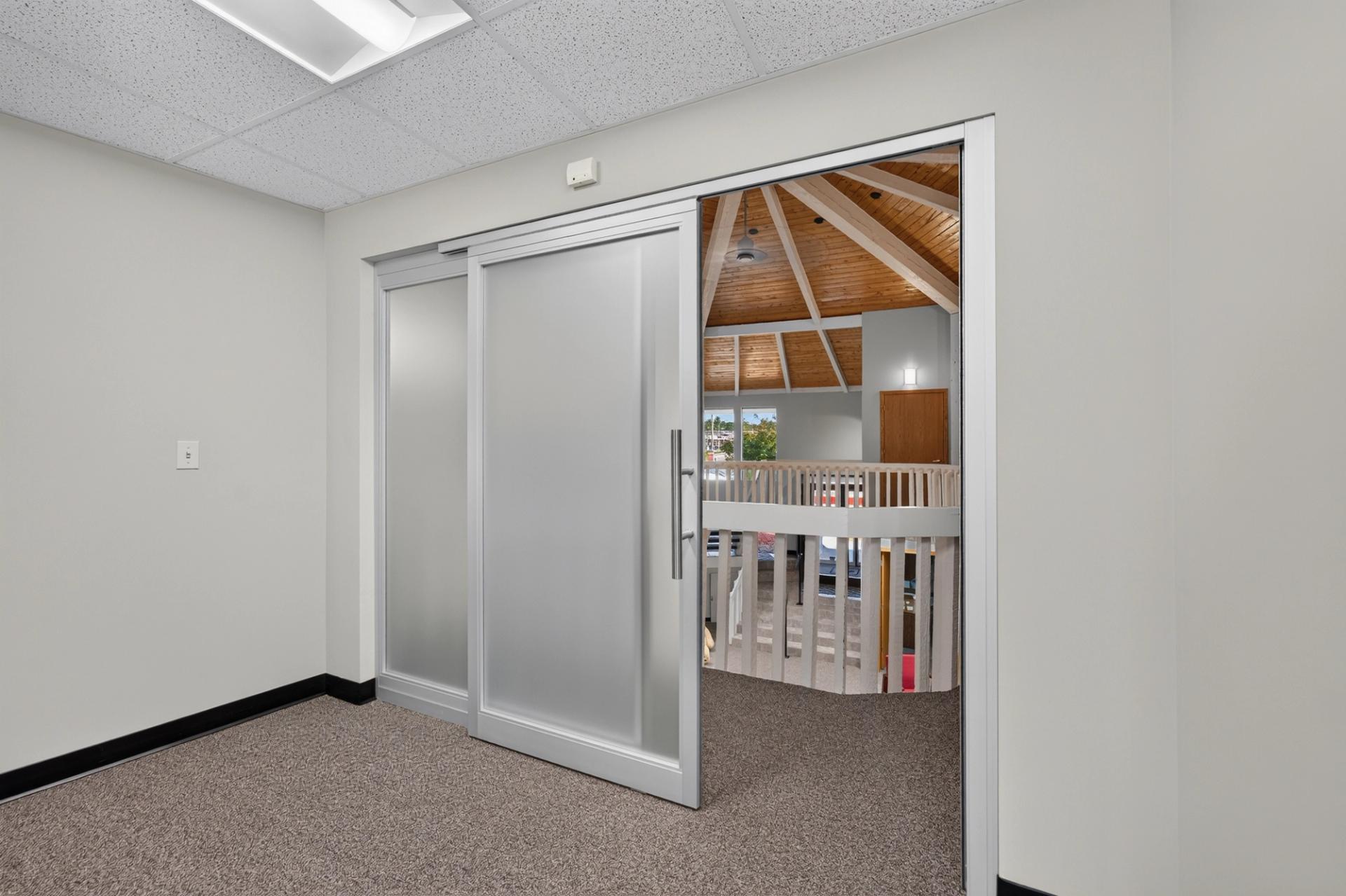ThinWall sliding door with frosted glass open onto the vaulted second floor landing at Tanya Patzner State Farm in Omaha