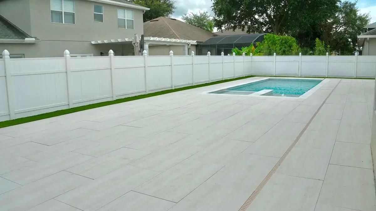 Modern pool surrounded by large light-colored pavers in an Orlando backyard