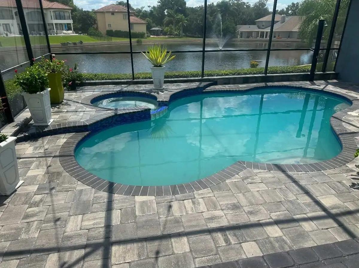 Brick paver pool deck surrounding a backyard swimming pool and spa in Orlando, FL