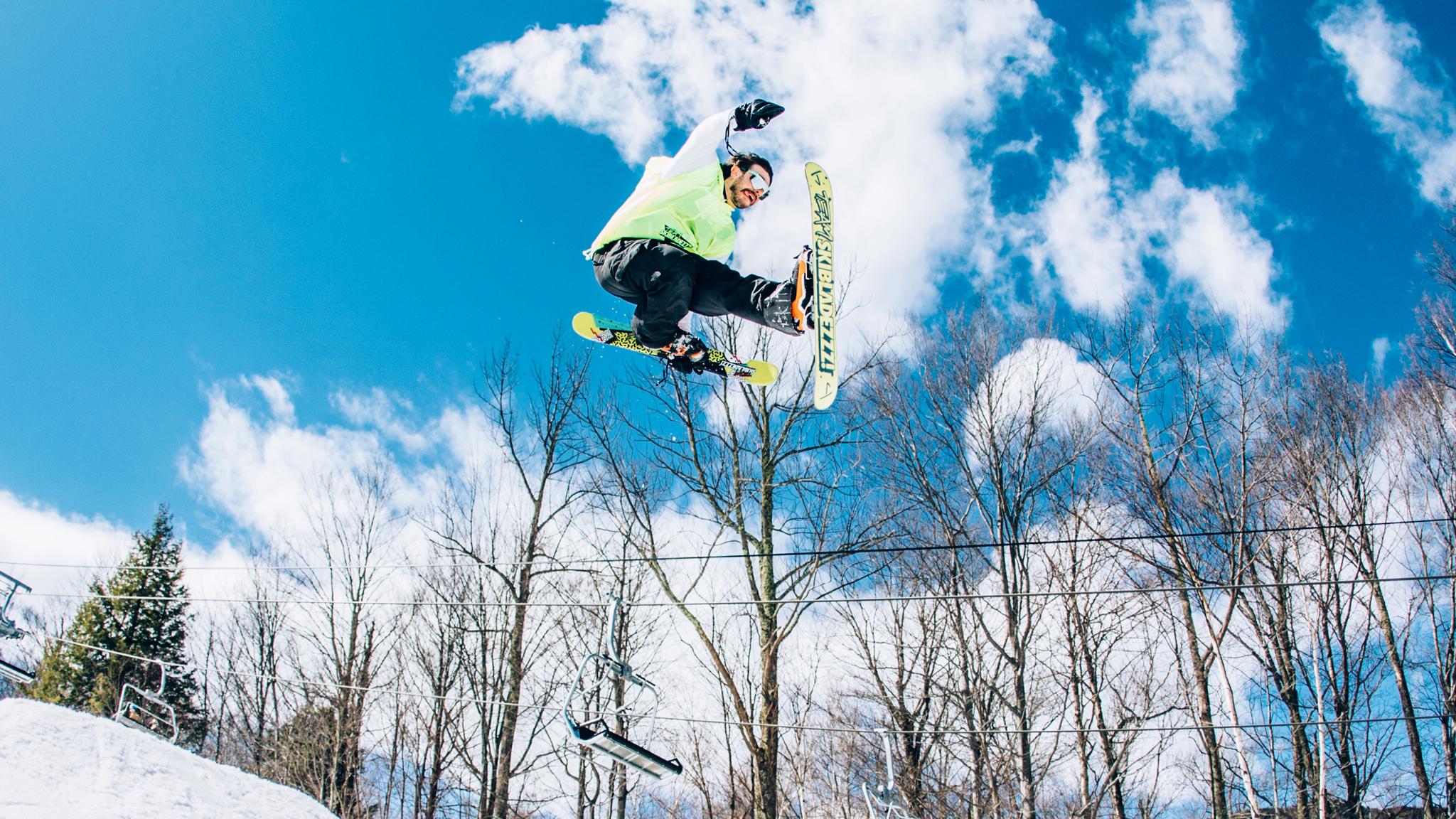 Skier in the air doing a liu-kang grab on the original bright yellow J skis skibladezzz