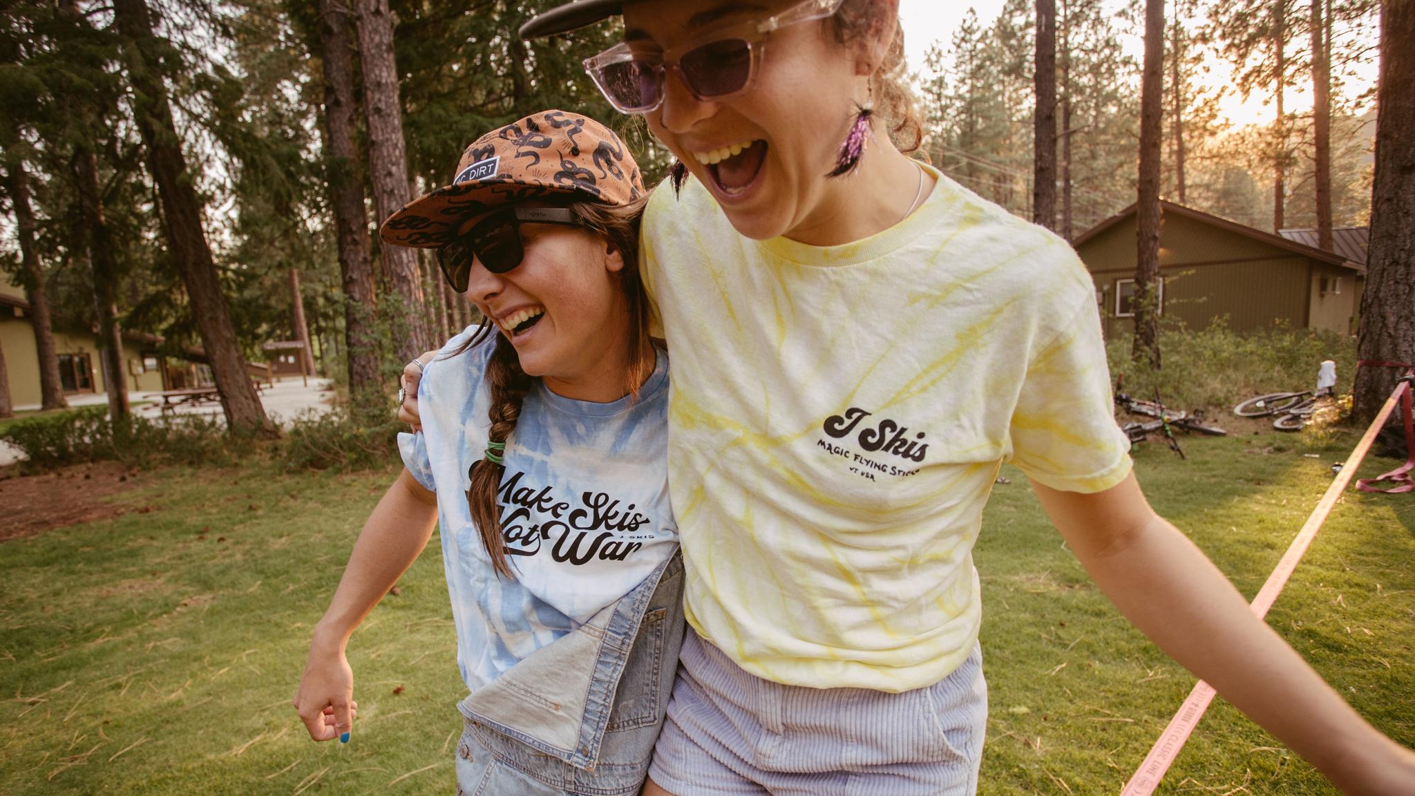 Two girls walking on a slack line wearing tye-die J skis t-shirts