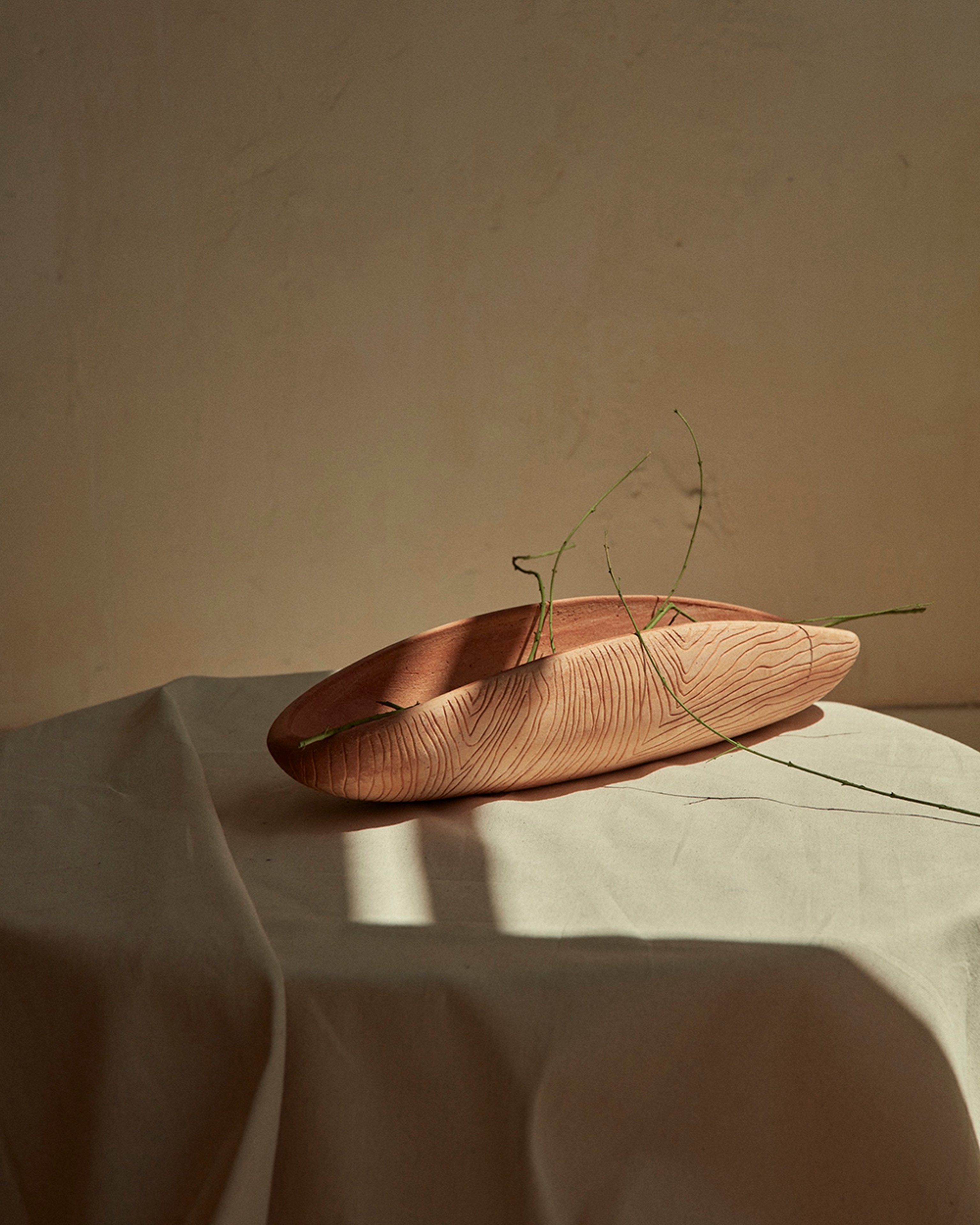 A terracotta object designed for New Volumes. Neutral background with dainty green florals