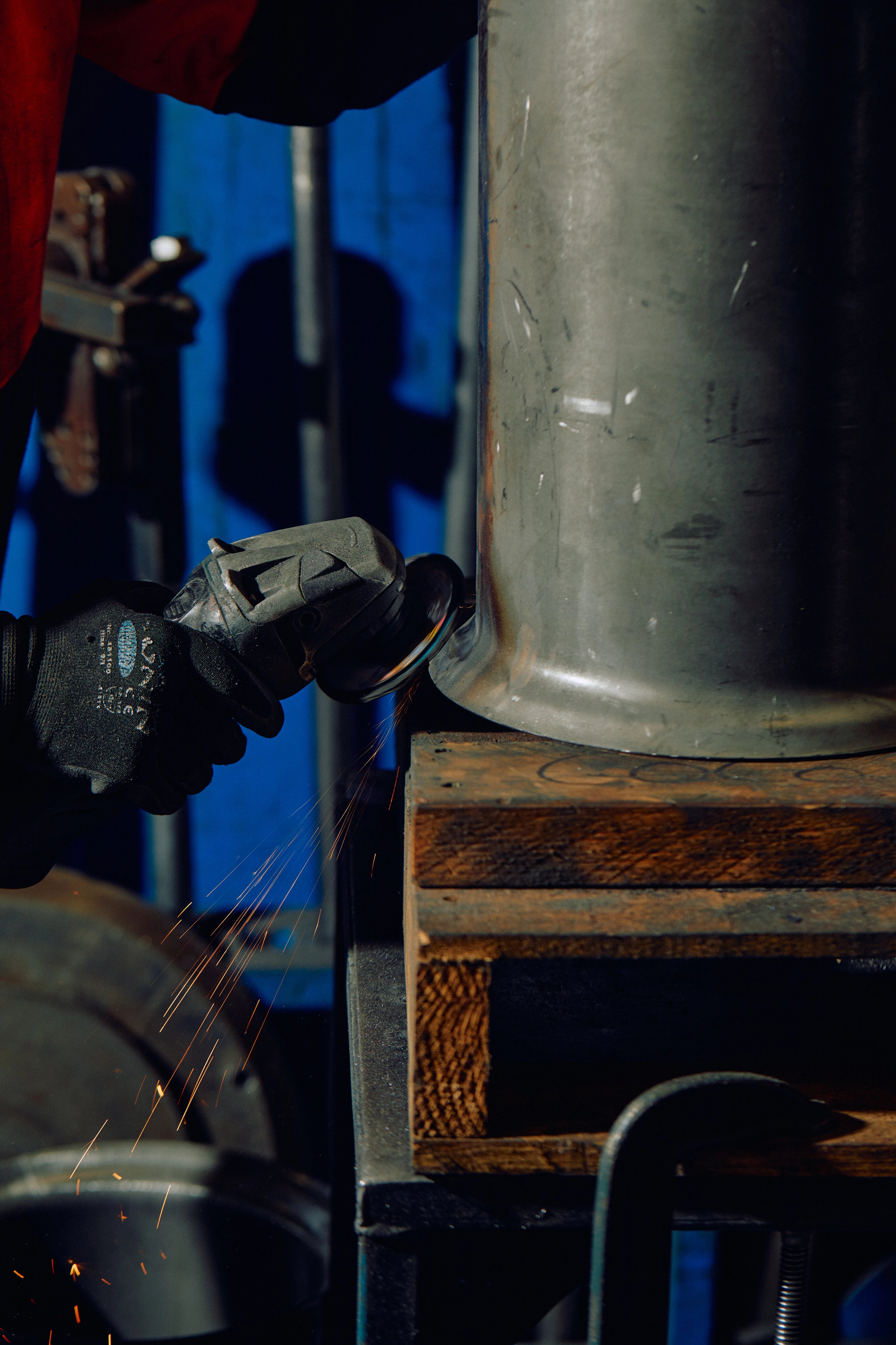 Hands use a tool to grind the edges of a metal drum