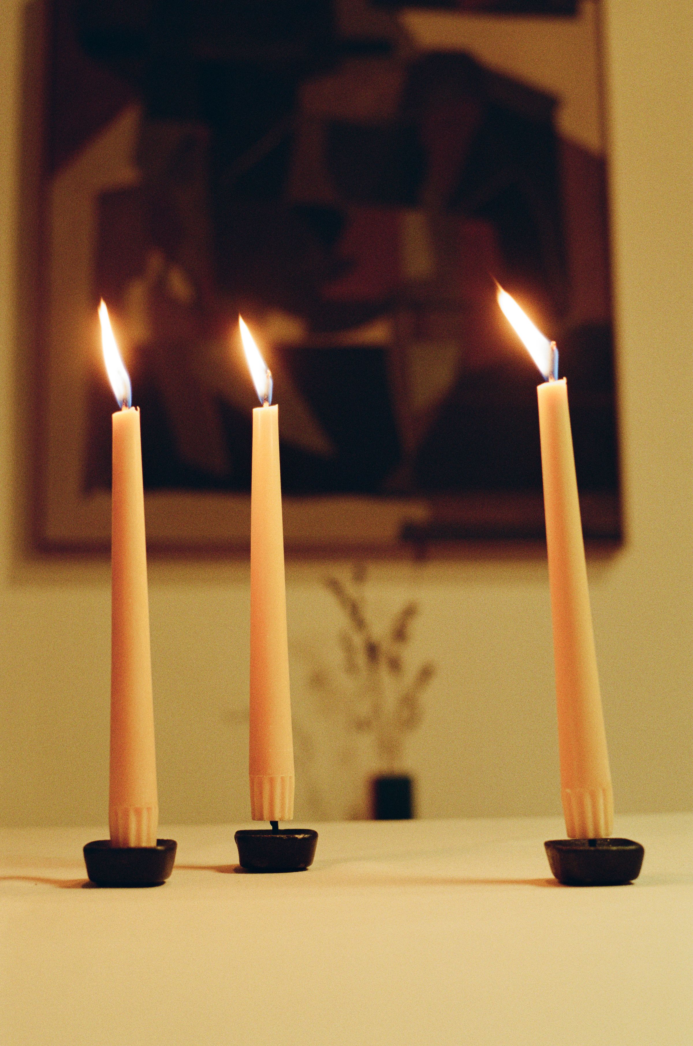 Small collection of lit candles on a table, creating a moody dimly lit and romantic vibe.