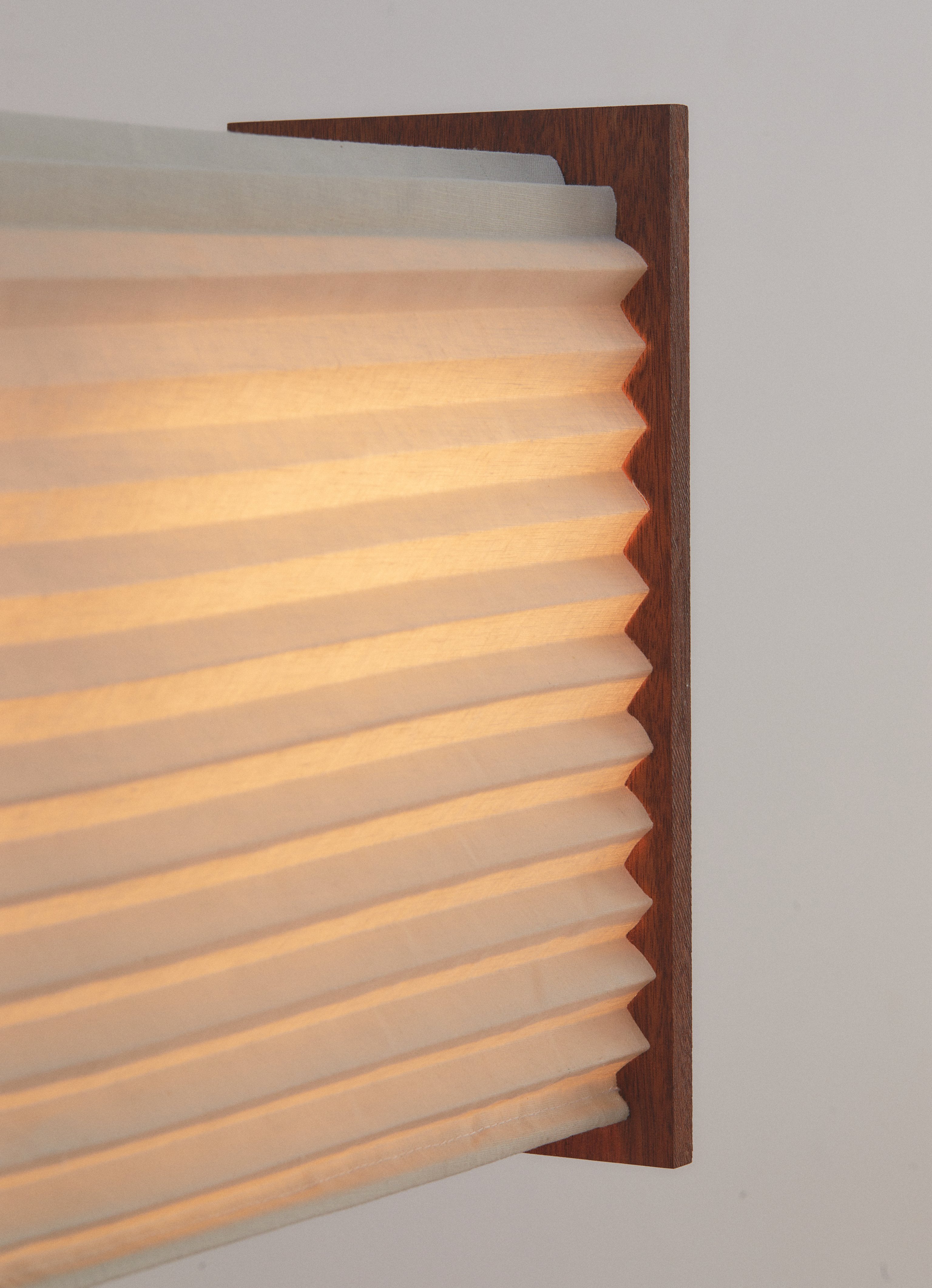 A detail of a pleated linen table lamp with a timber frame