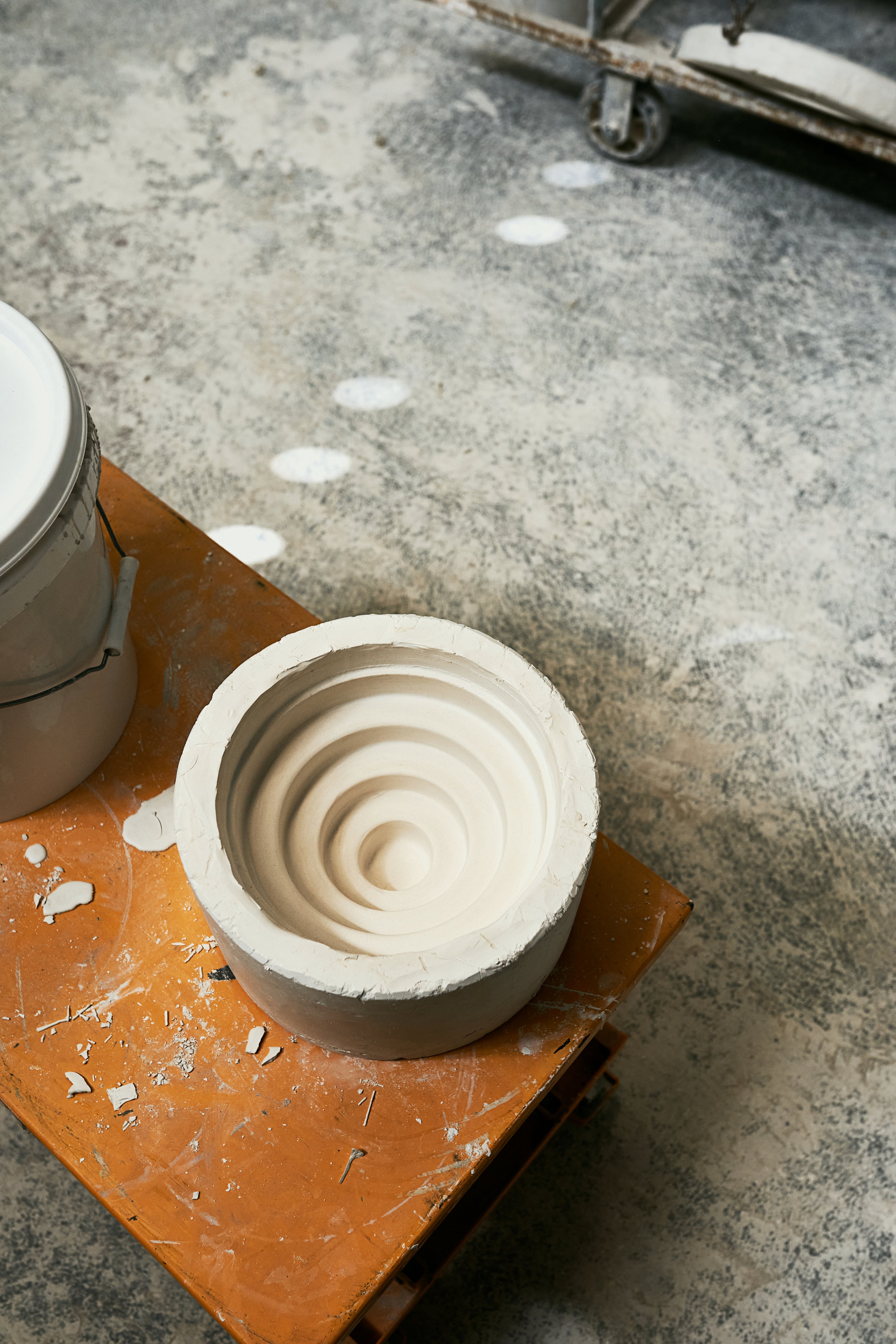 A Honey pendant ceramic slip-casting mould sits on a messy table in a factory.
