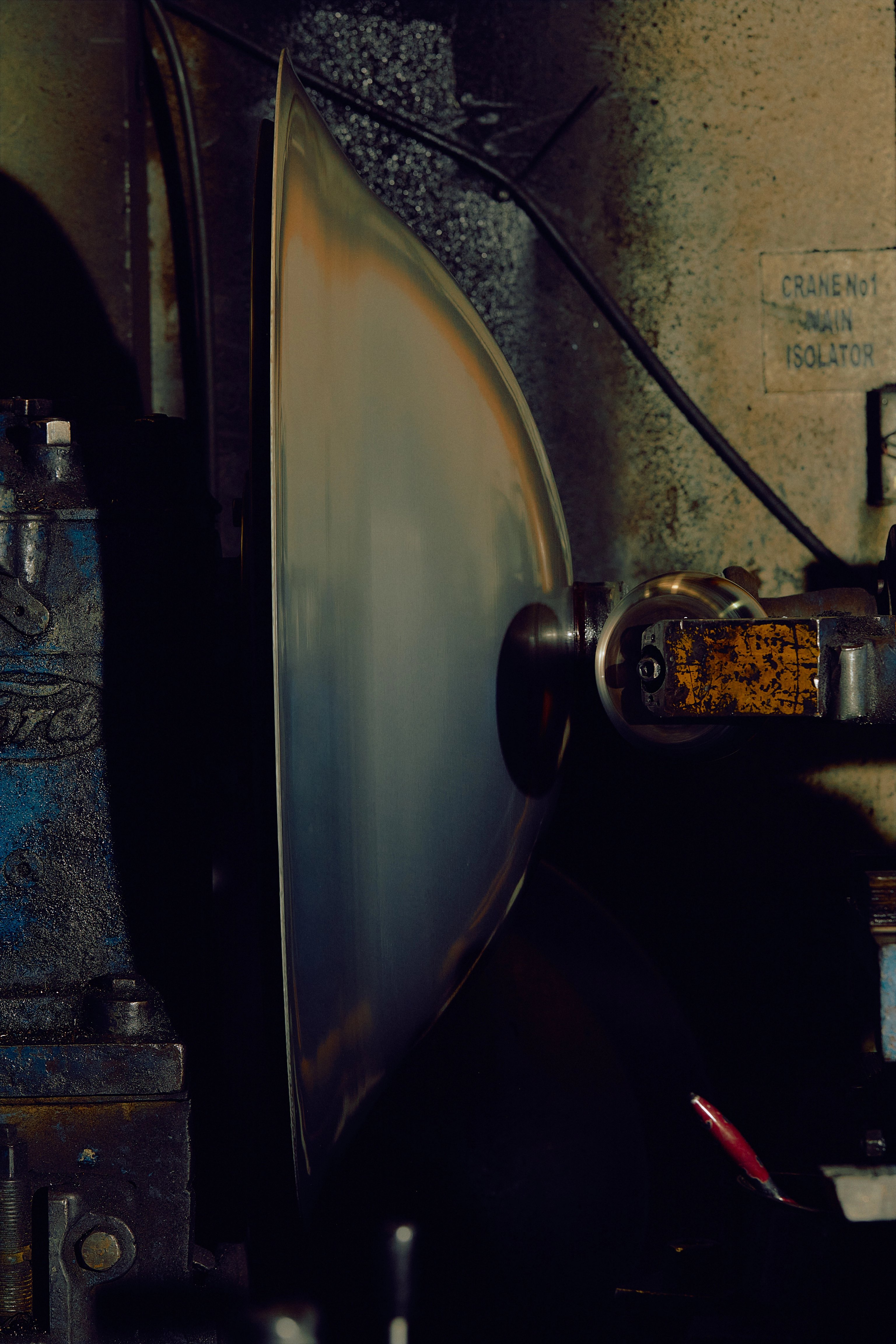 A large rounded metal form is spun using a roller on a lathe