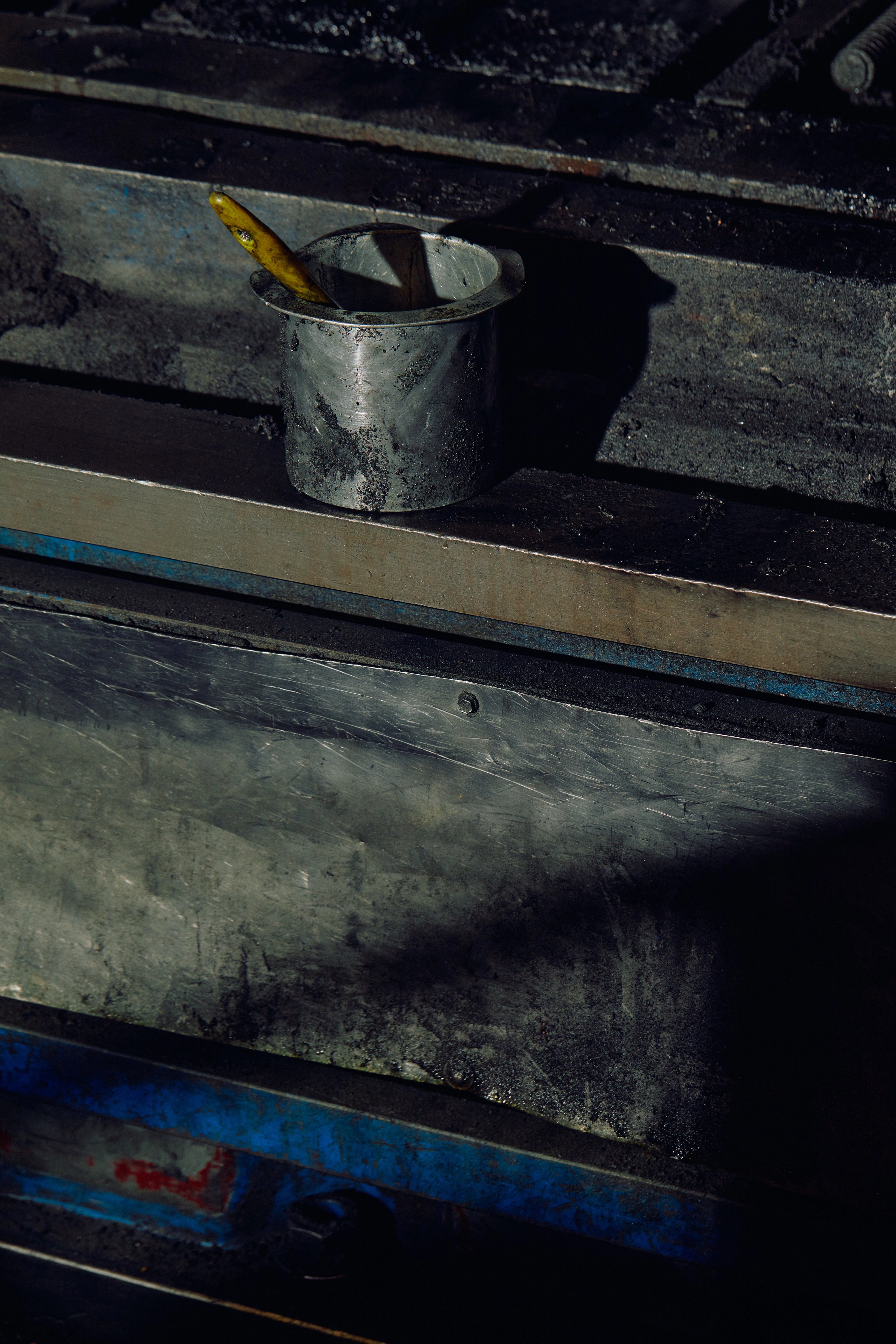 A pot of oil with a paint brush sitting on a metal ledge
