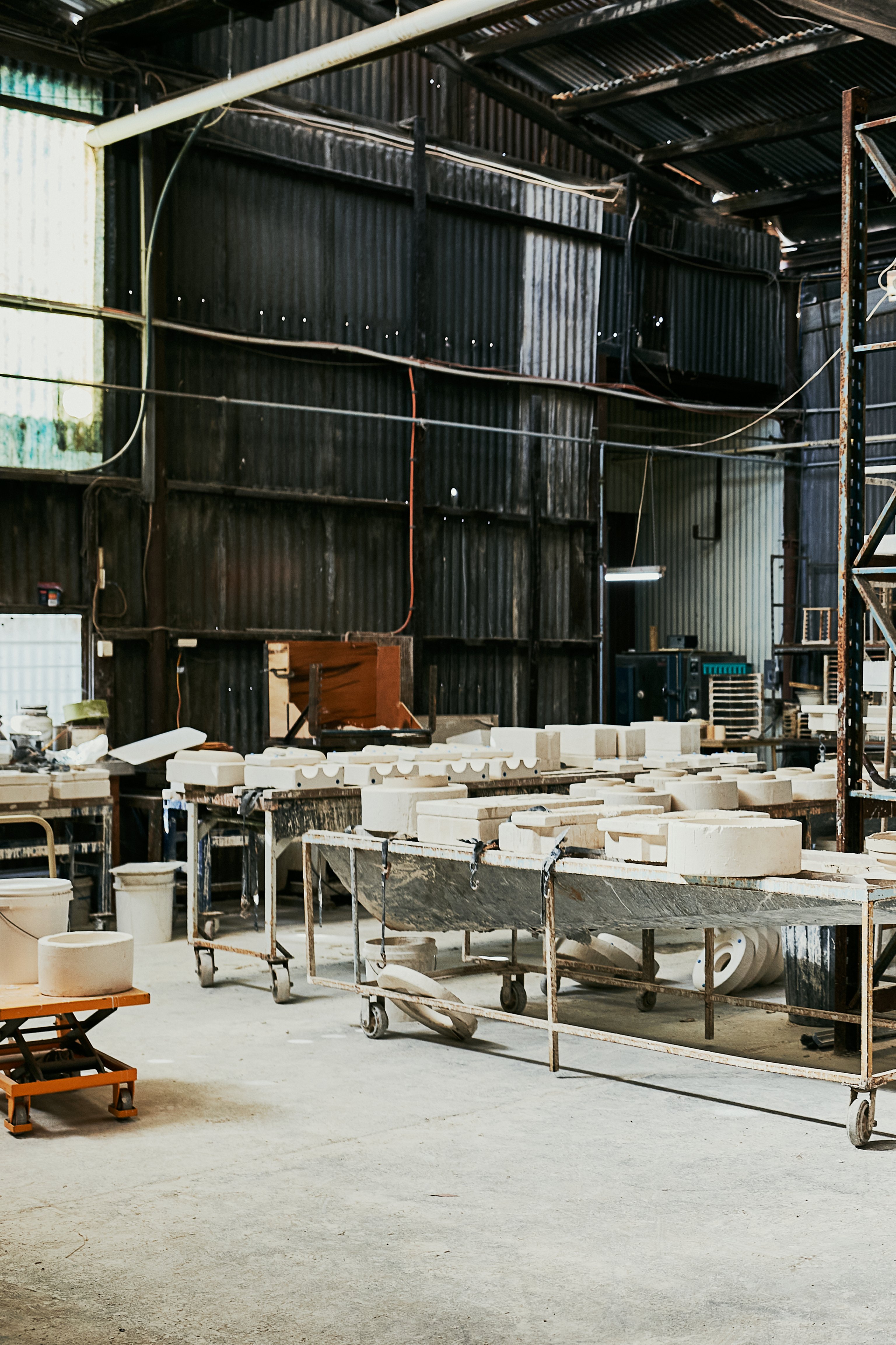 Bendigo Pottery's large factory with industrial tables on wheels holding ceramic components that are drying.
