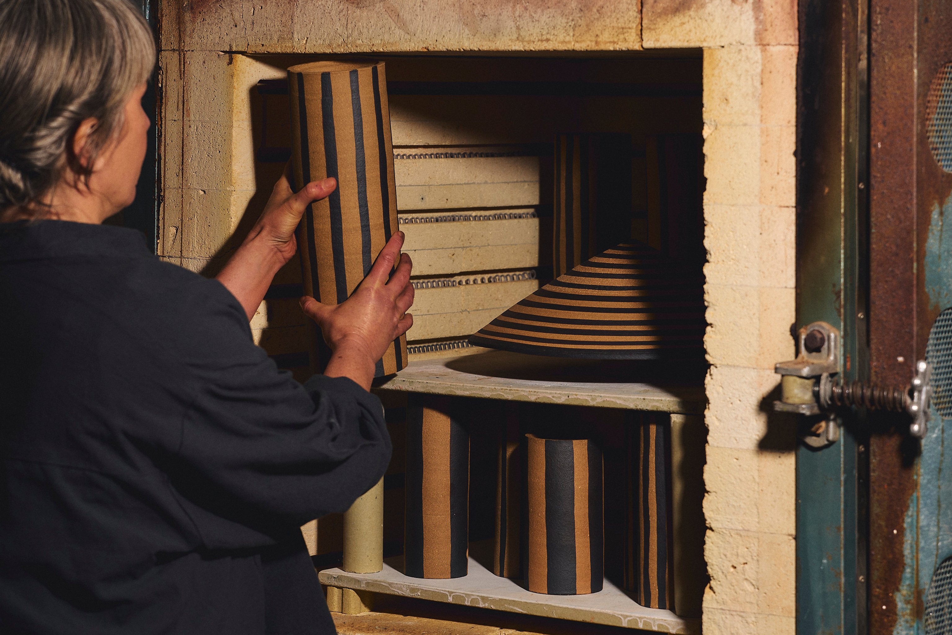 Ceramicist Belinda Wiltshire placing Dancer ceramics into the klin.