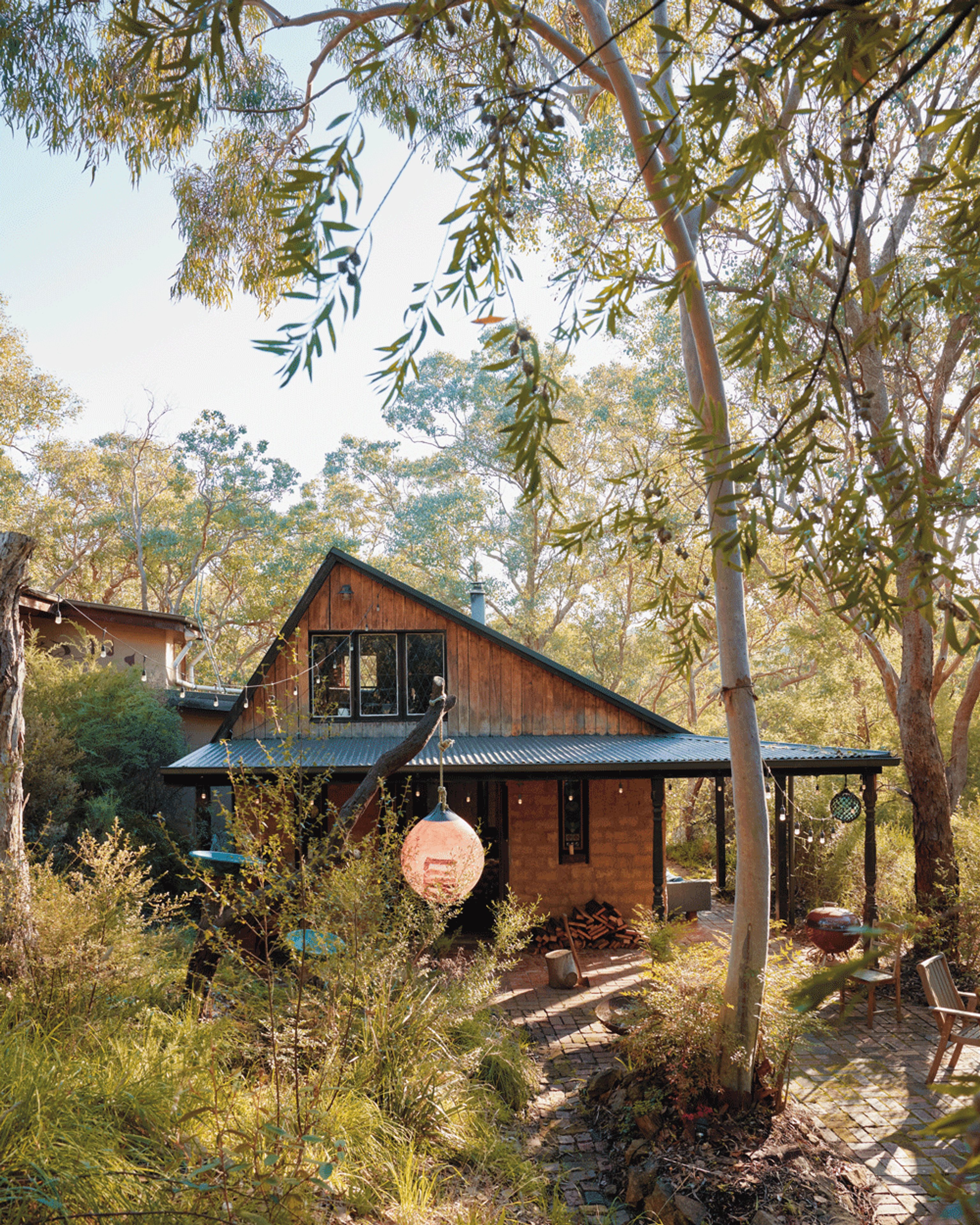 A mud brick and timber home with an angular roof sitting amongst dense Australian bush.