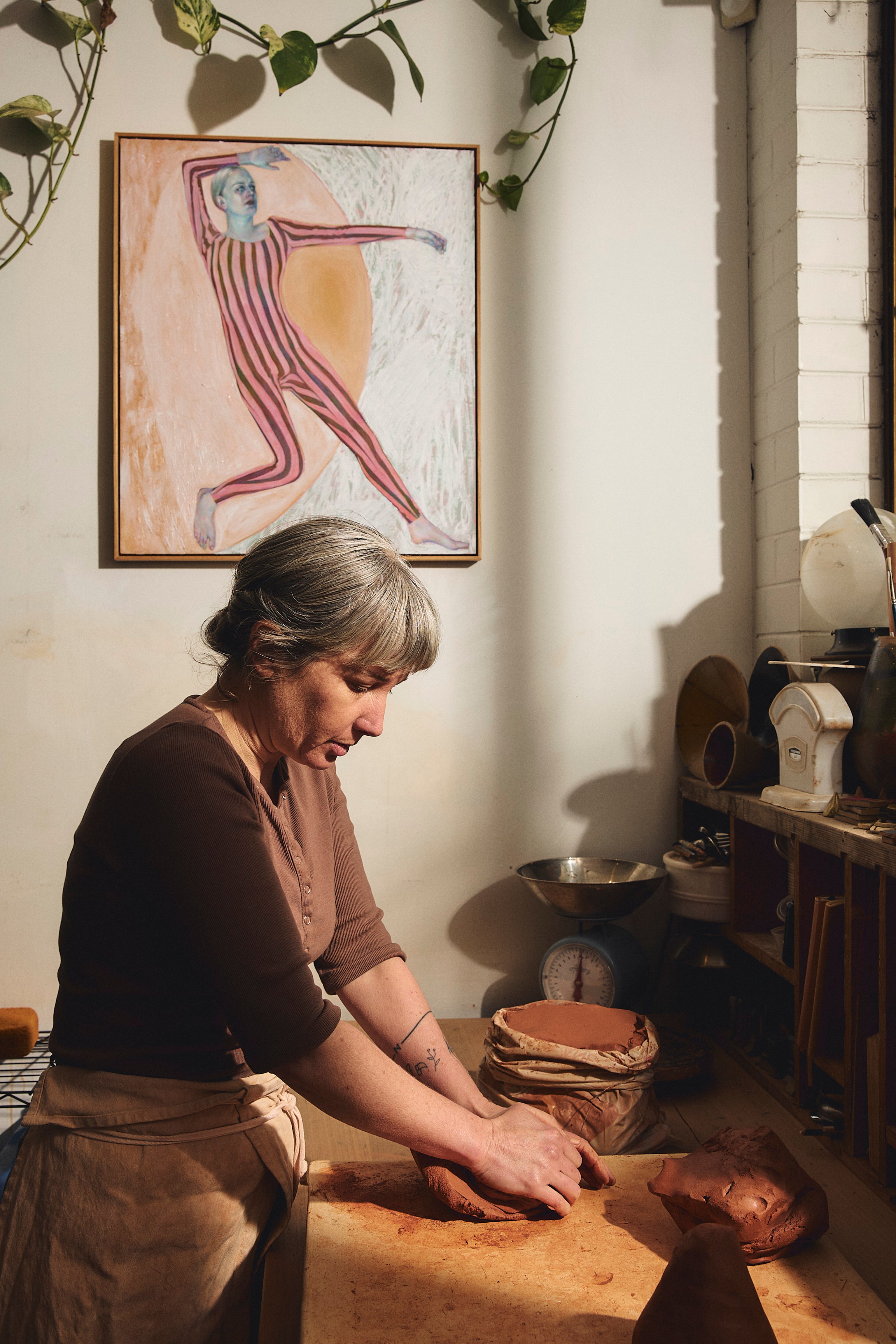 A portrait of Jessica Lillico and Sean Fennessy sitting at a dining table. Behind them on a rendered brick wall is a large abstract artwork.