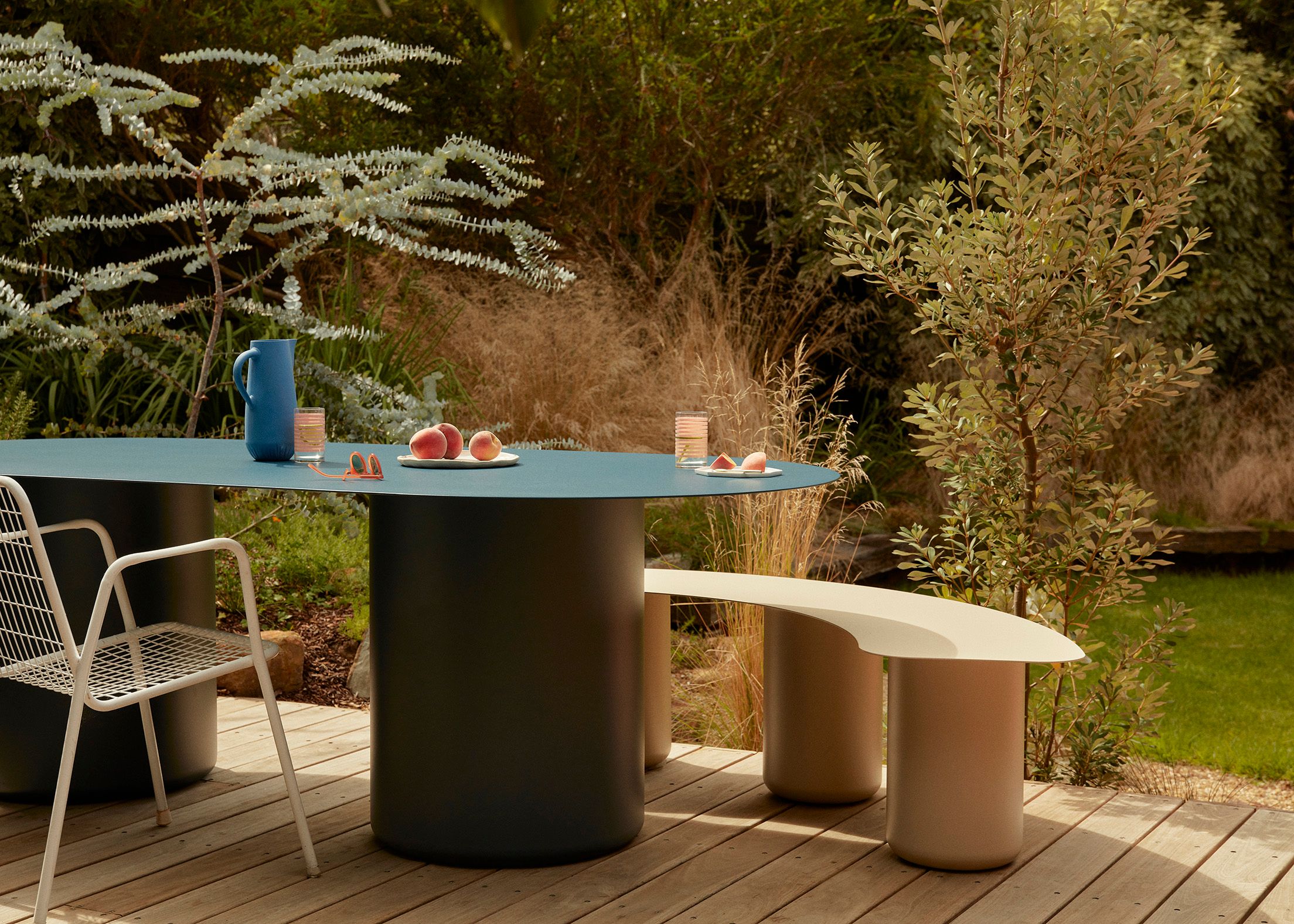 An outdoor dining setting with a blue dining table and beige coloured stool made from steel