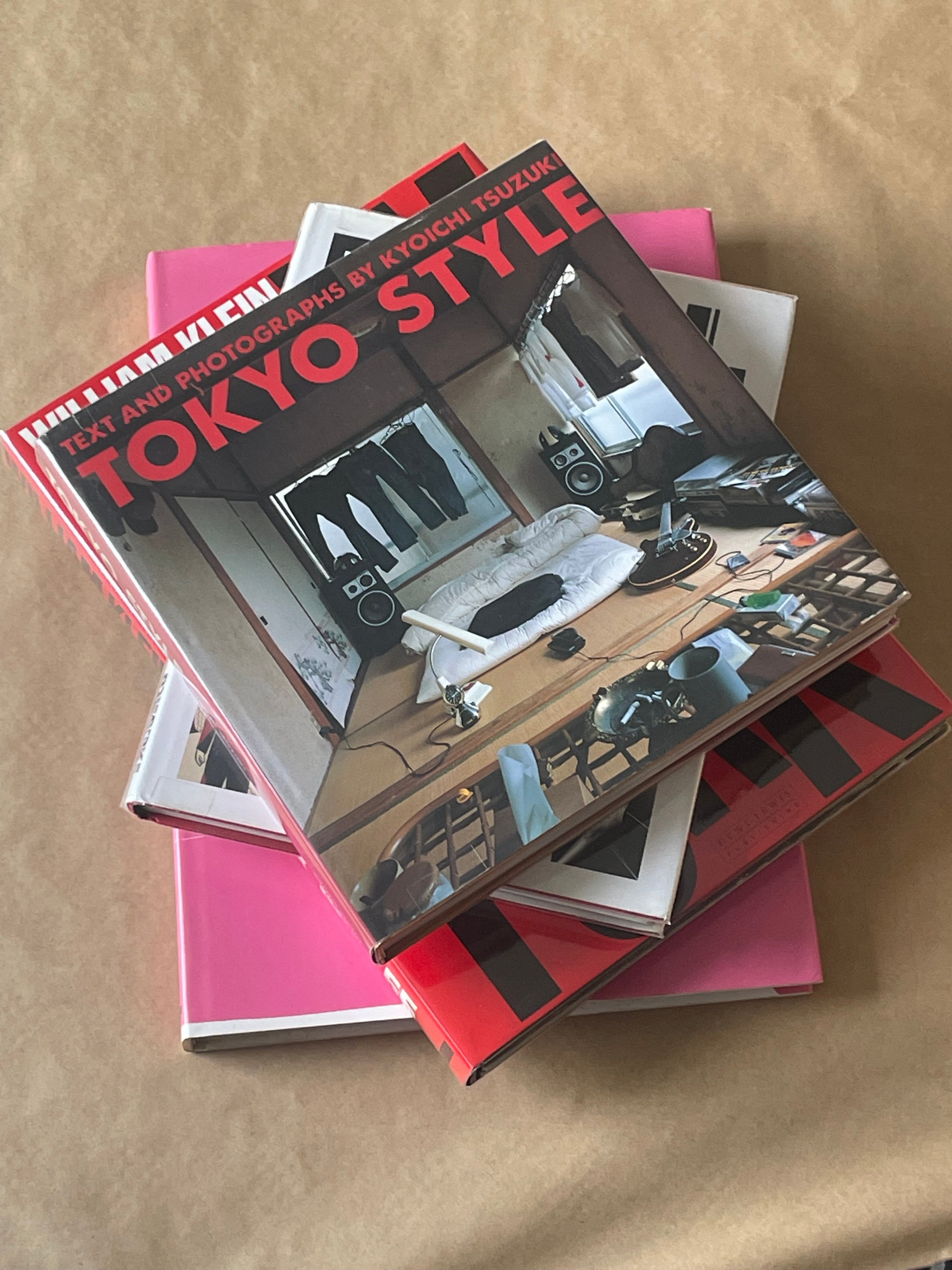 A richly textured modernist home interior with art filling the walls and books filling the bookshelves. Two black leather armchairs and a timber coffee table furnish the room.