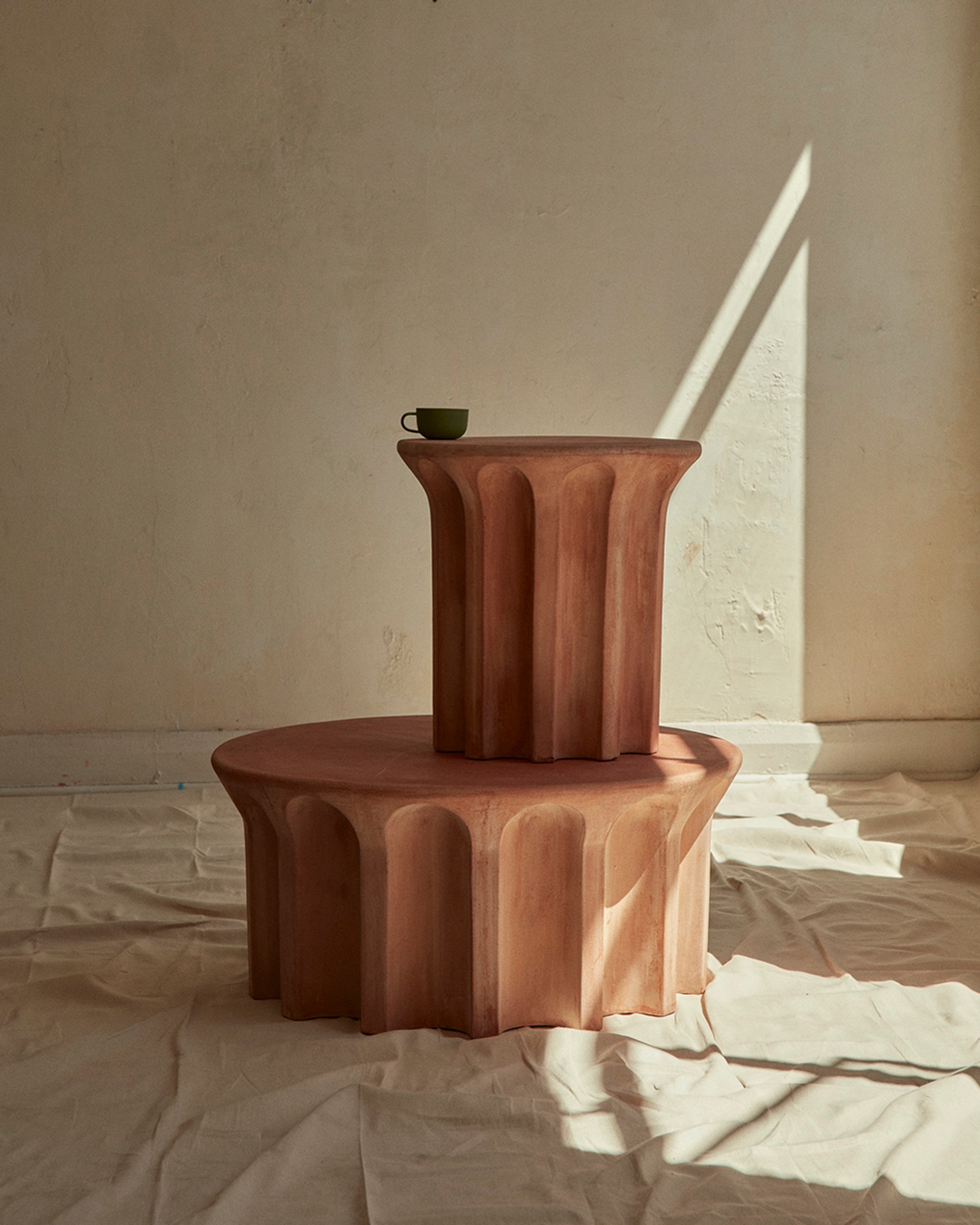 Two terracotta detailed tables stacked on top of each other in a neutral room.