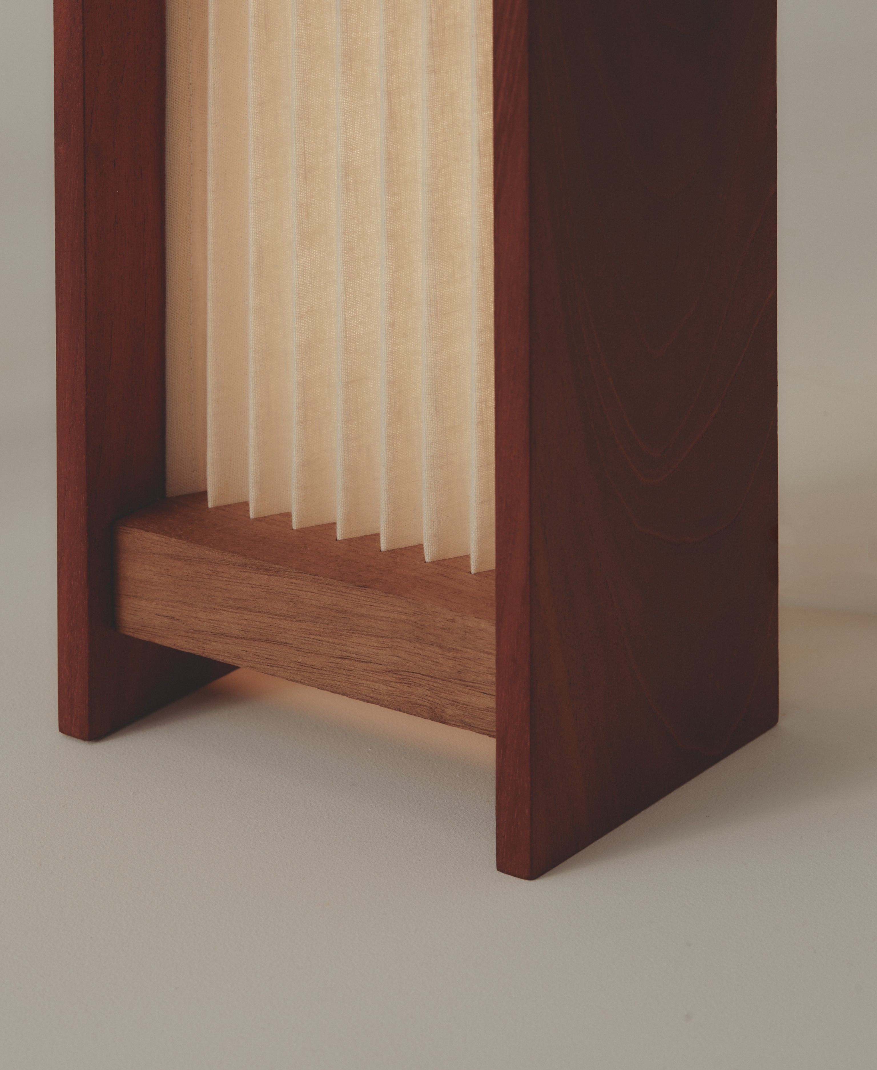A detail of the bottom of a pleated linen and timber wall light