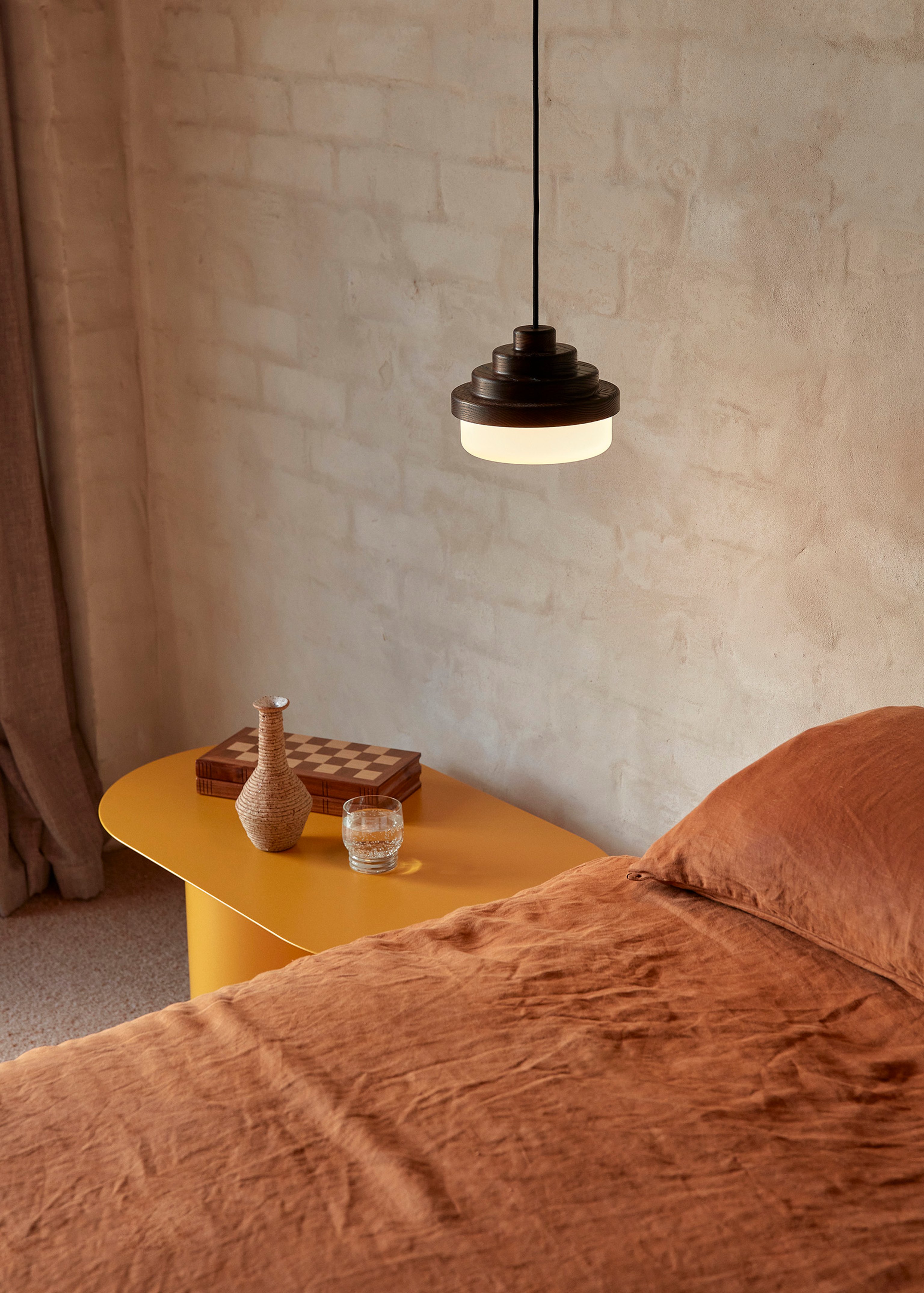 A Honey pendant light above a bed, with a