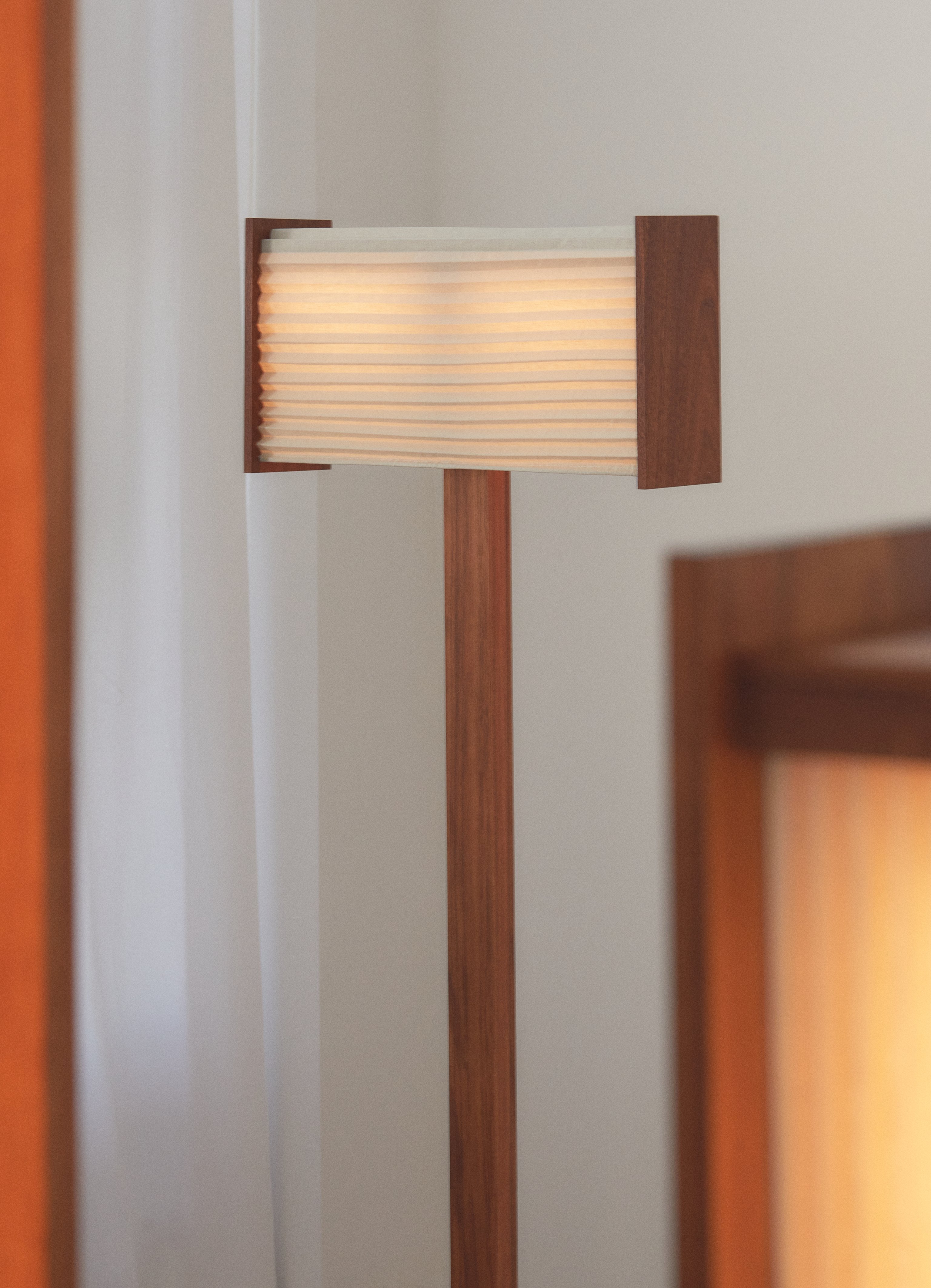 A contemporary pleated linen floor lamp with timber base and warm glow