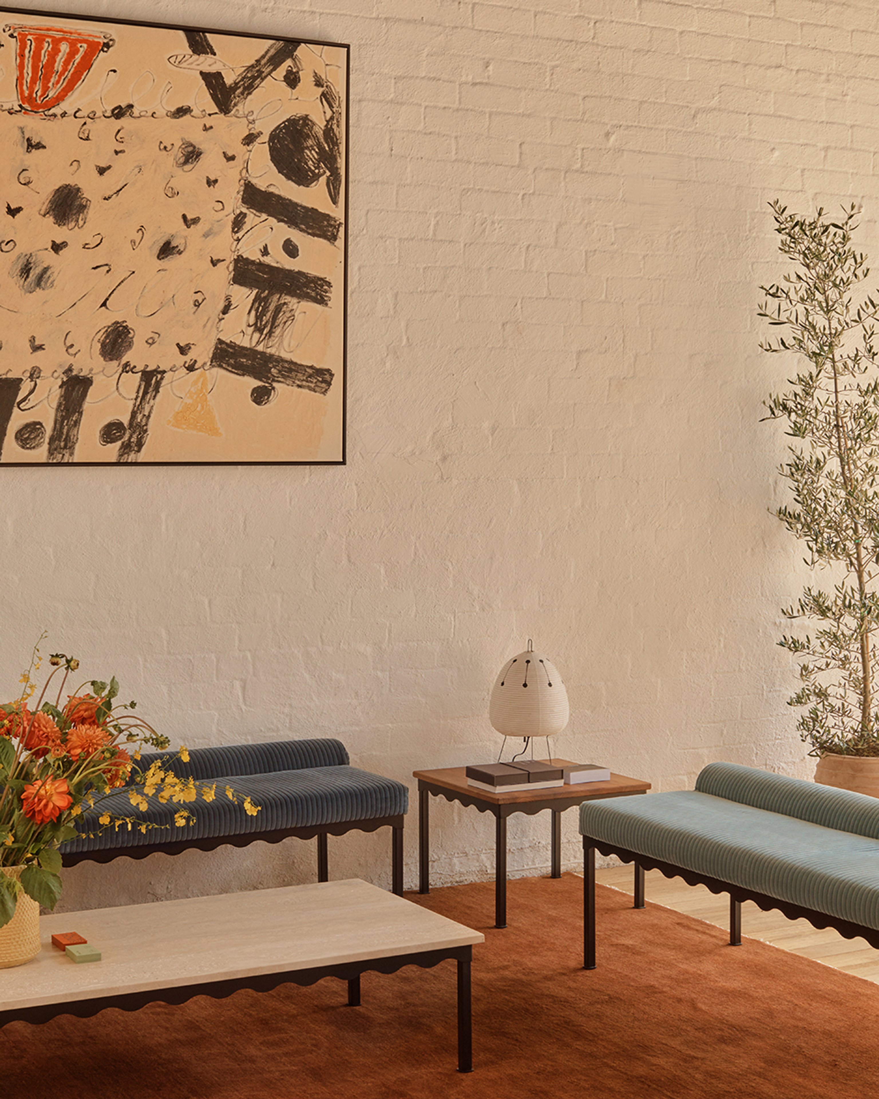 two upholstered benches with light blue and dark blue corduroy fabric and black steel frames. In the room there is also a stone Bellini coffee table and timber top side table