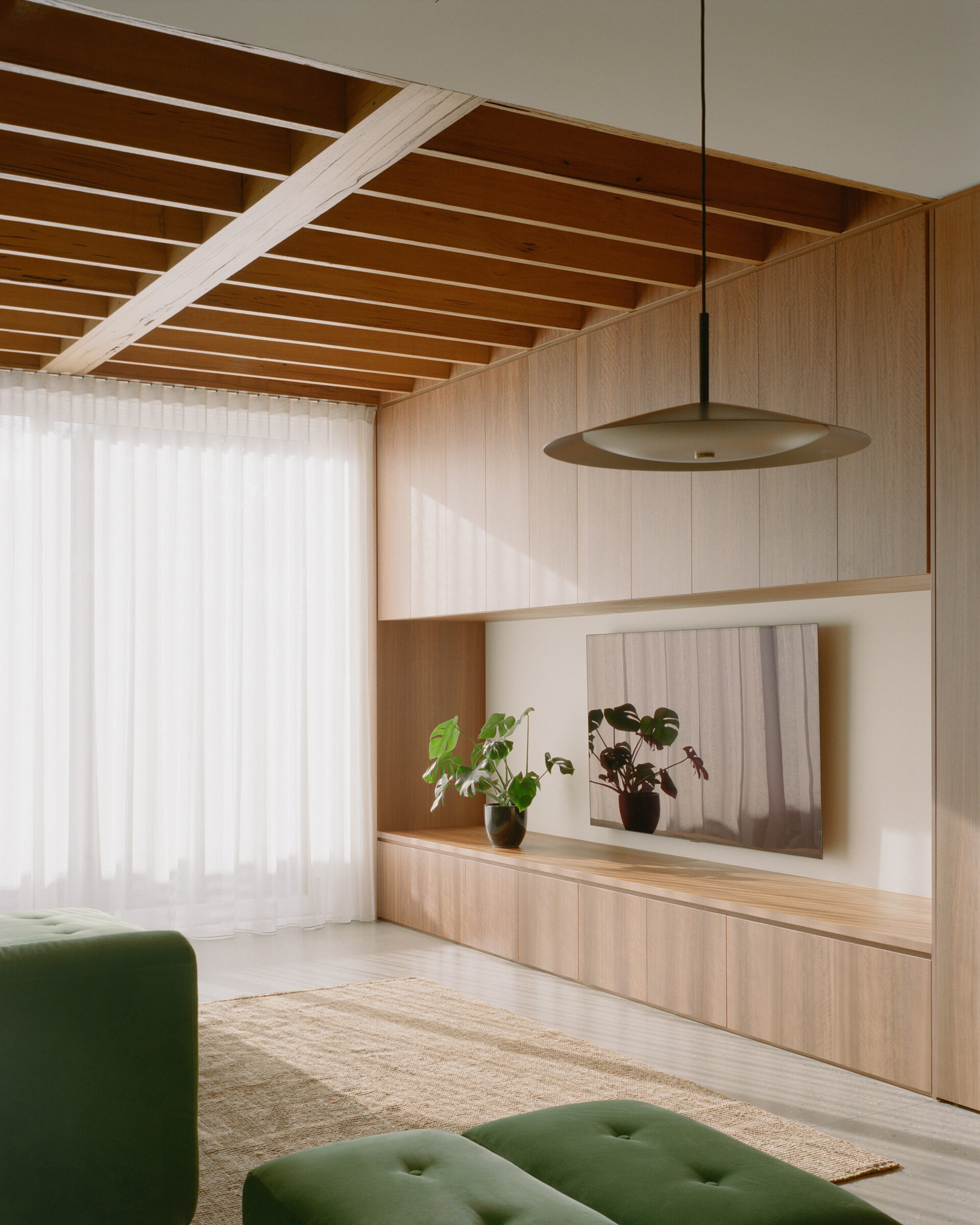 Burnley House by Field Office Architecture, featuring a eucalypt Broad Pendant and plush green sofa.