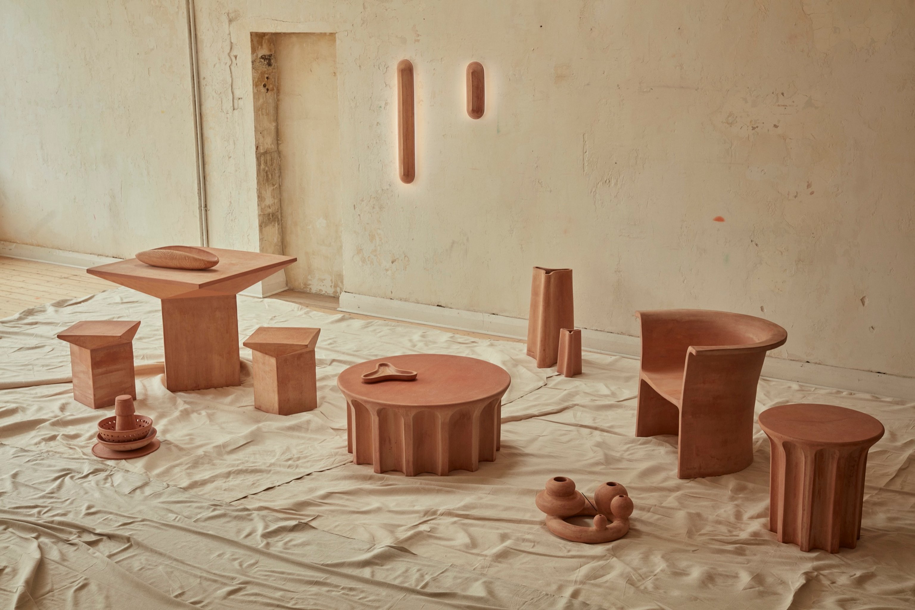 New Volumes collection 02 in a neutral coloured room. A collection of terracotta furniture pieces, lighting and objects