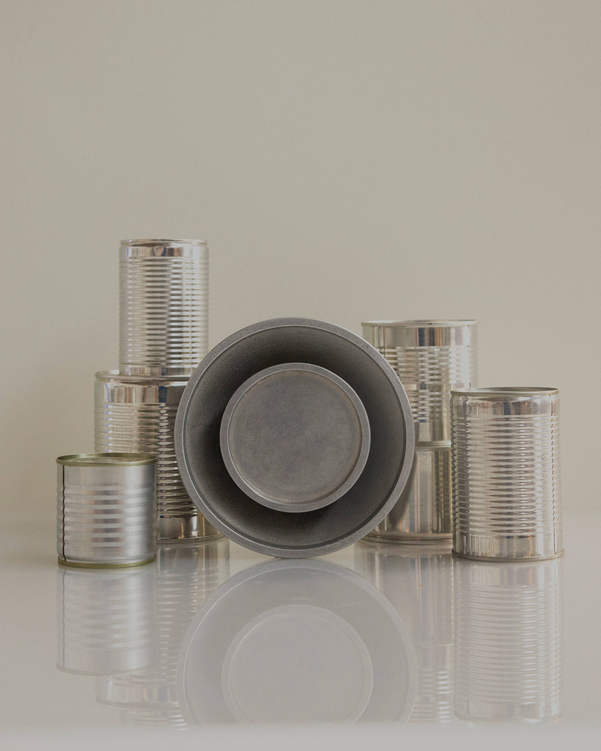 Chorus Wall Light in Aluminium resting against a collection of silver cans.