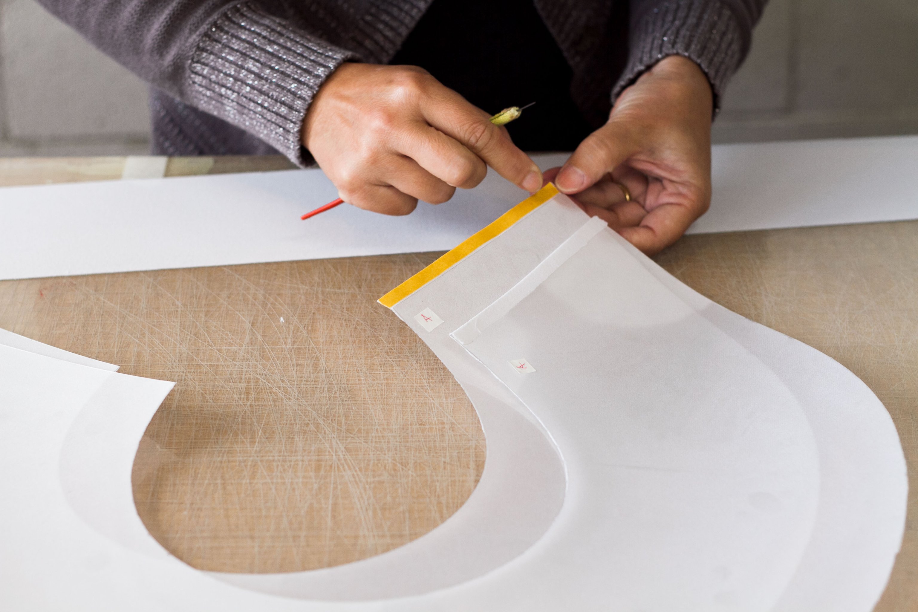 White fabric shades being laminated onto acrylic shapes and taped together