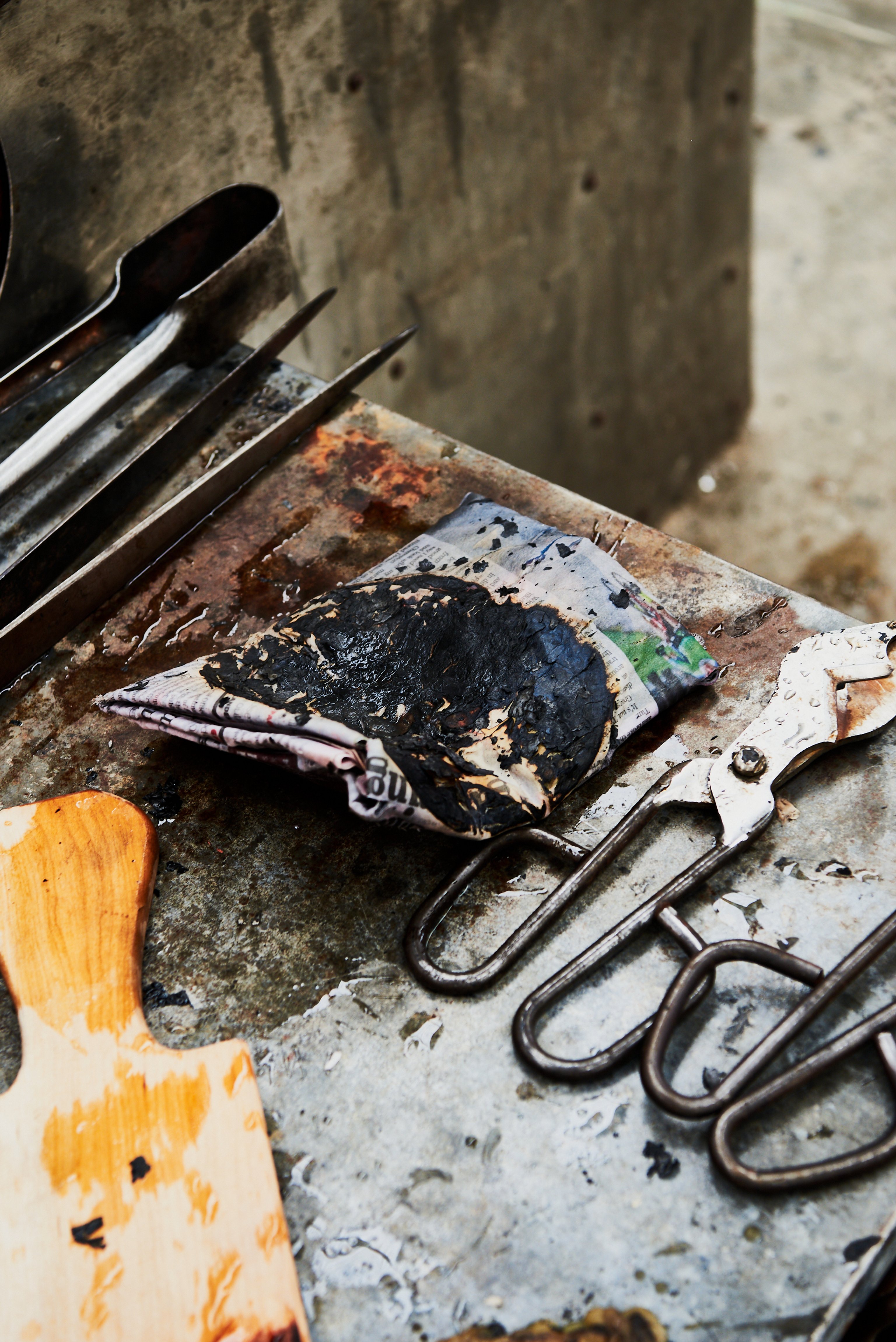 Glass blowing tools sitting on a messy metal workshop bench.