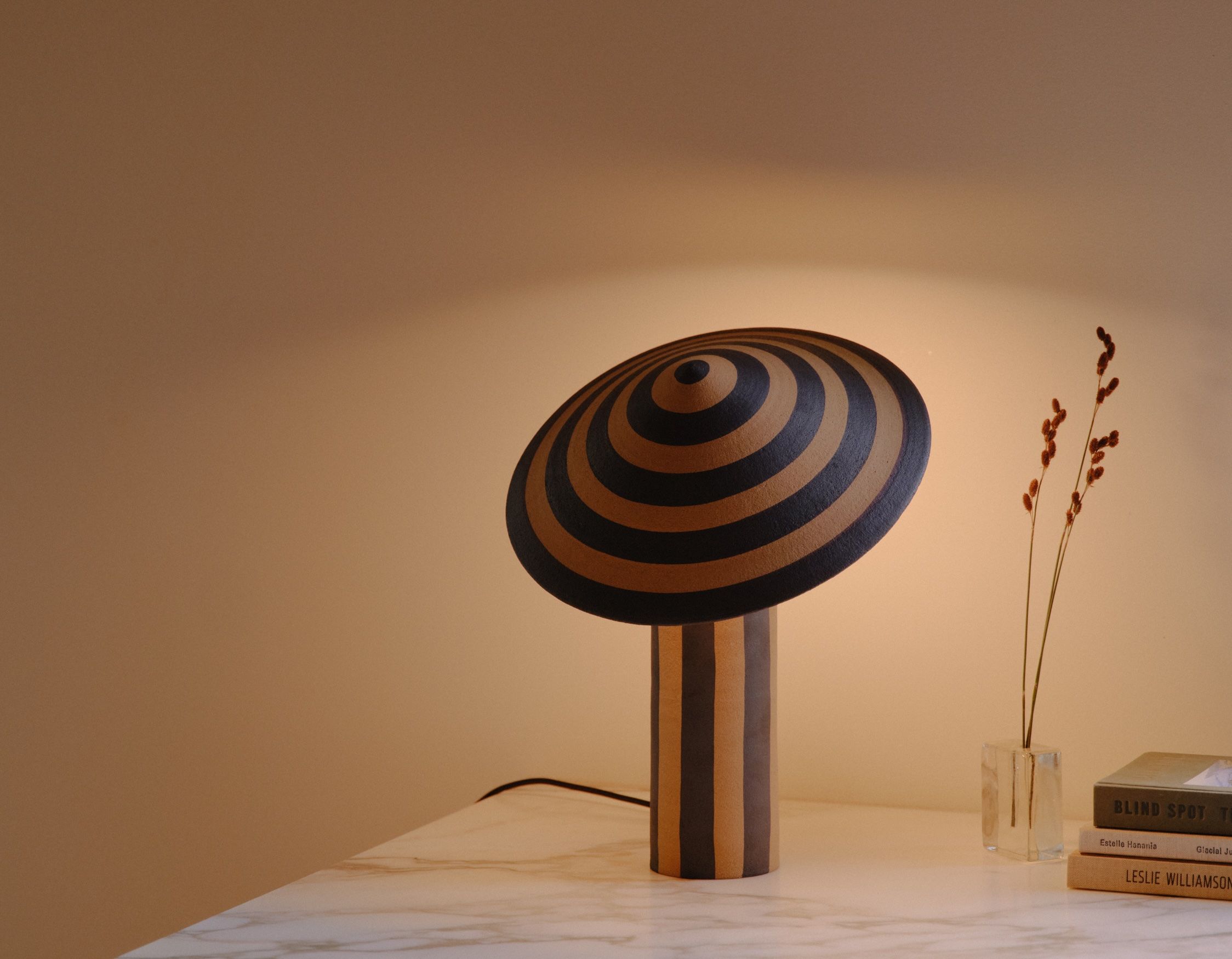 A pale blue wide corduroy upholstered bench in a dimly lit room with blue and white tile flooring