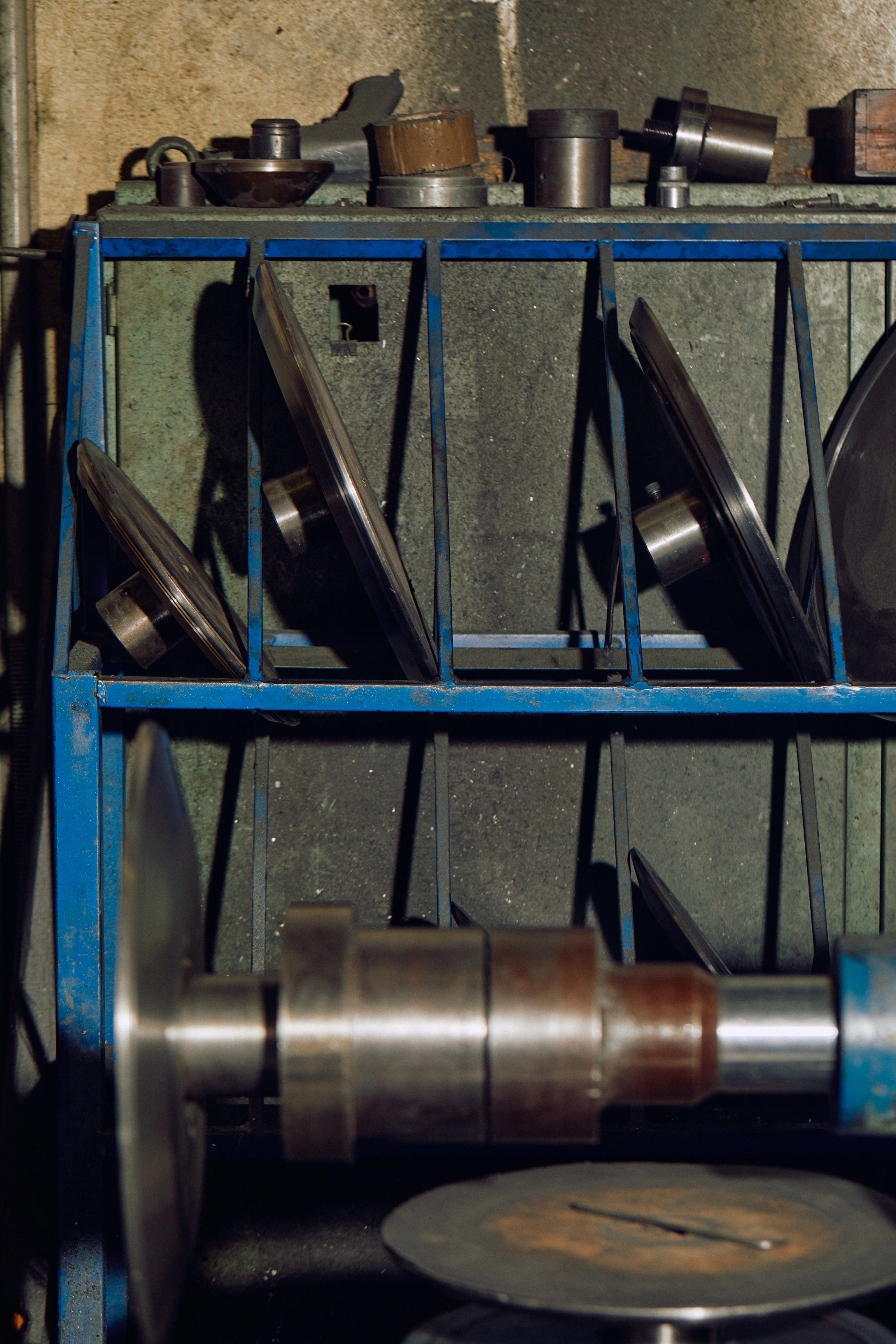 A blue shelf of tools and metal moulds with a metal lathe in front