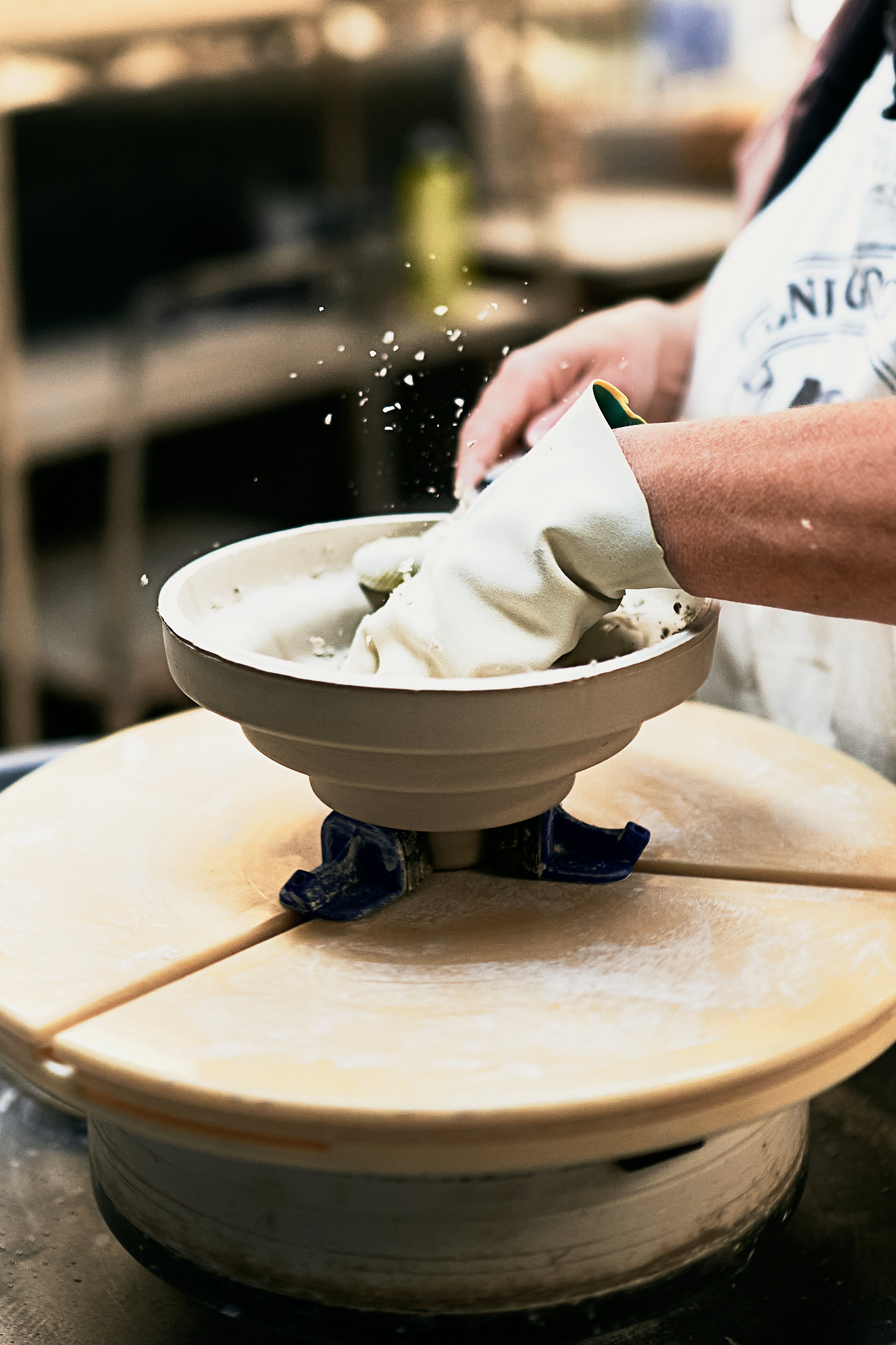 A ceramic Honey pendant light is being trimmed by hand on a wheel