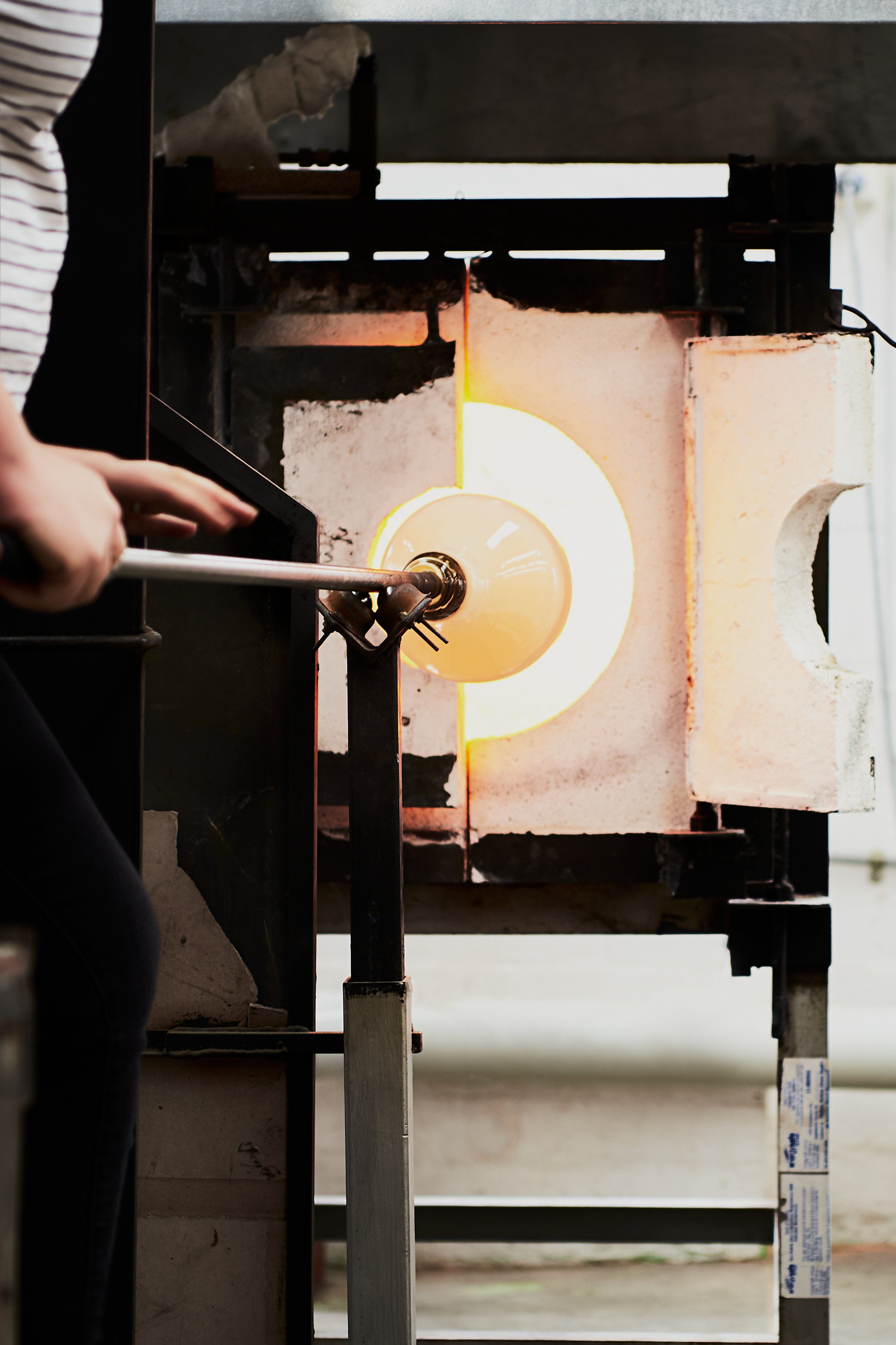 Glass on the end of a blow tube being heated in a furnace.