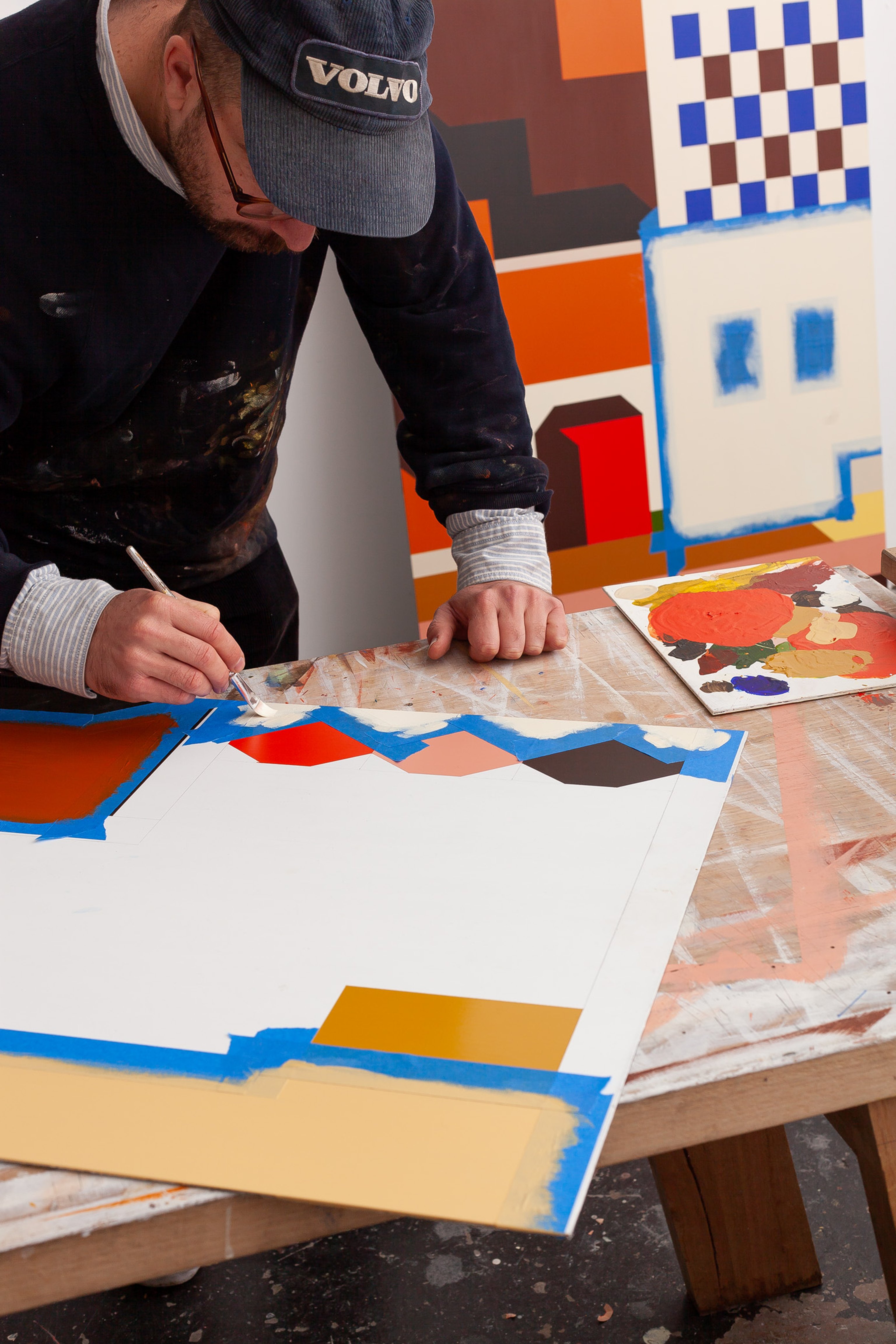 Mark Alsweiler working on a painting, consisting of browns, oranges, yellows and red..