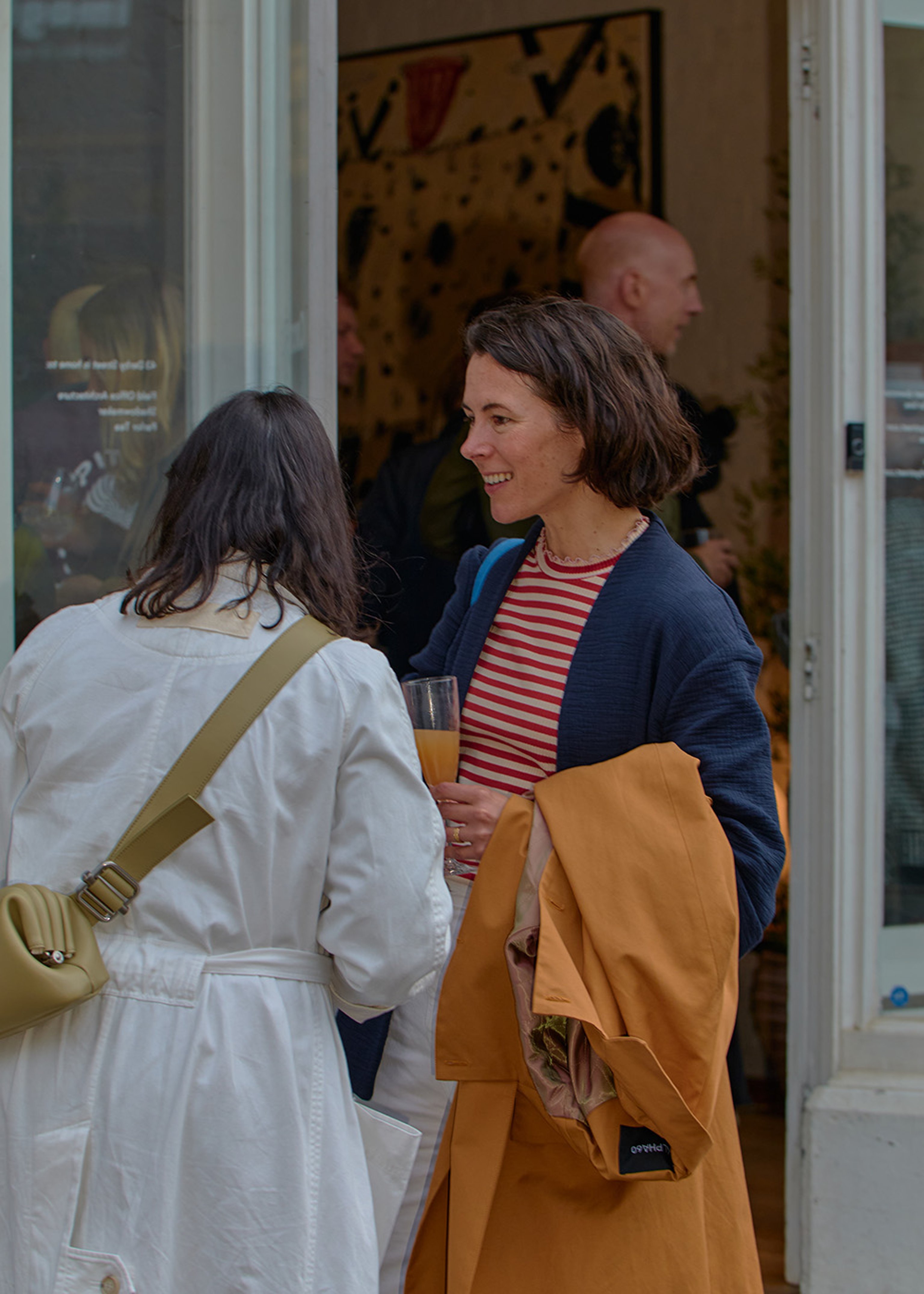 The outside of a small shop. Two women chatting outside the entrance