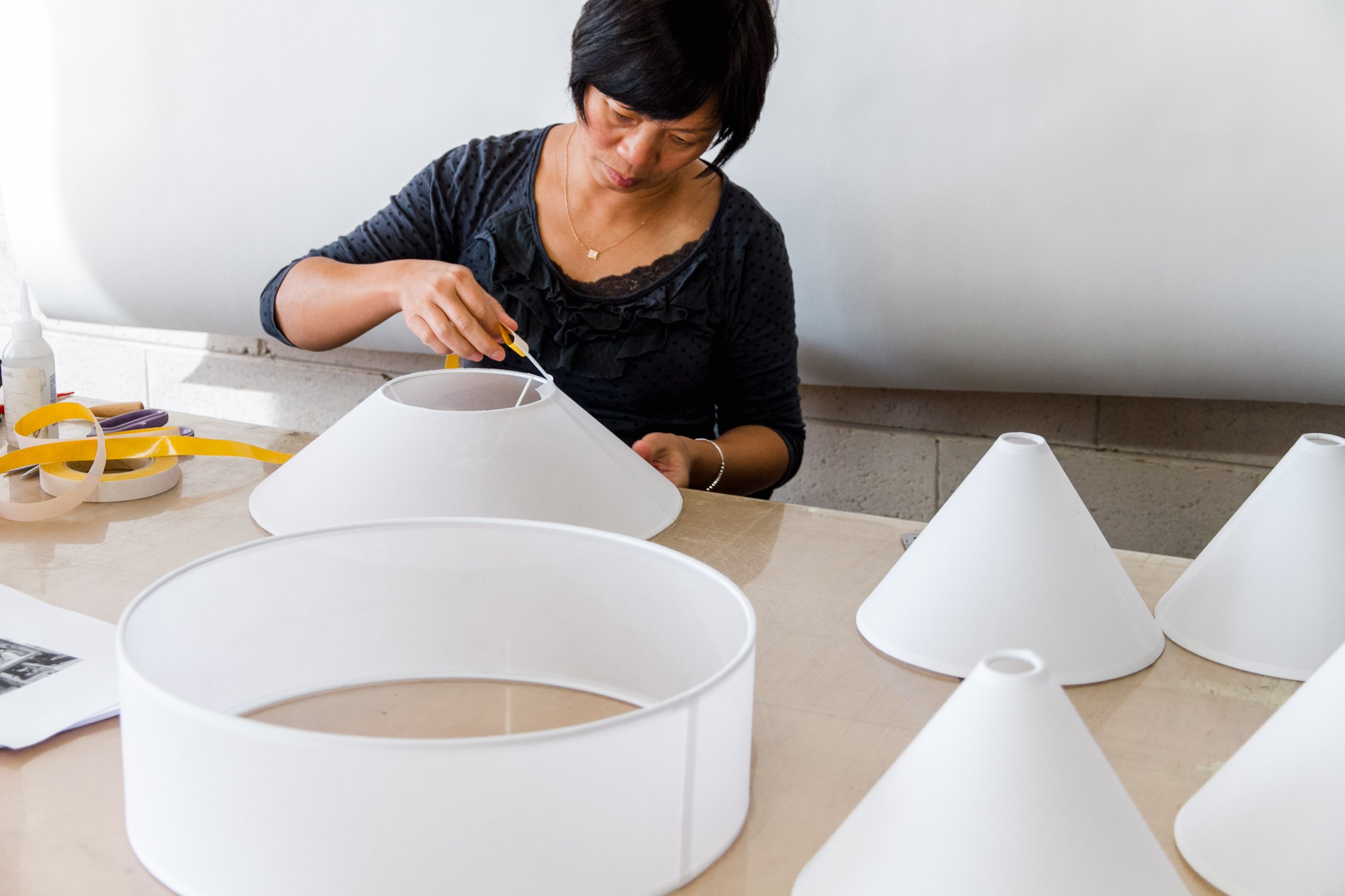 A woman constructing a series of white fabric shades around wire frames