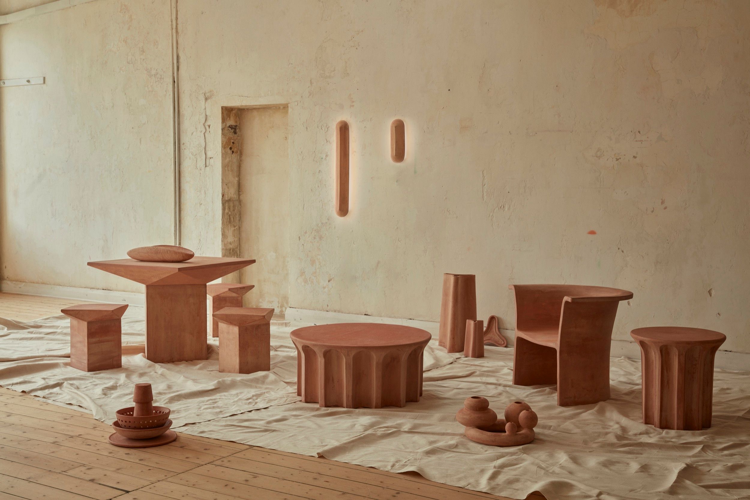 New Volumes collection 02 in a neutral coloured room. A collection of terracotta furniture pieces, lighting and objects