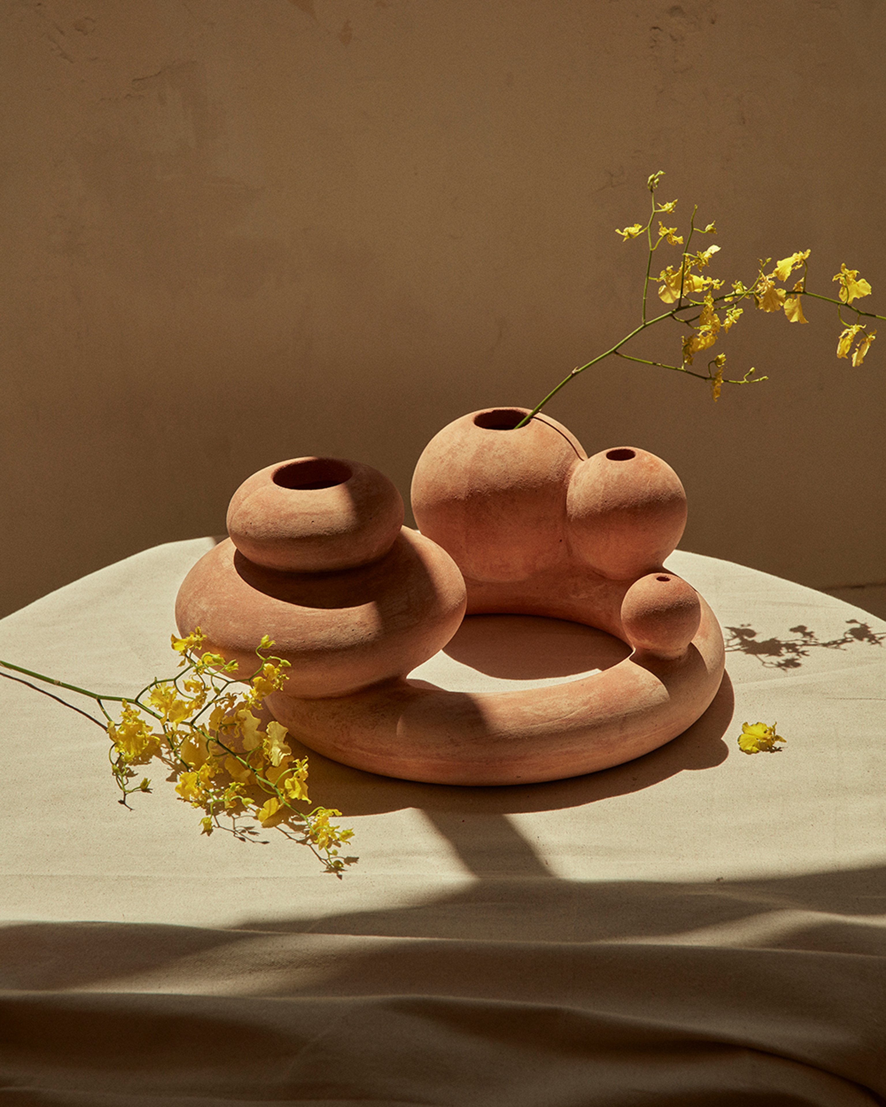 A terracotta object designed for New Volumes. Neutral background with dainty yellow florals