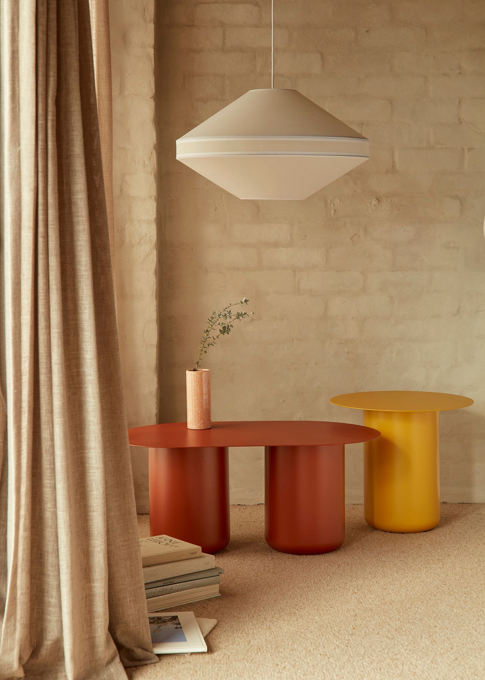 a neutral colour room with a large modern mesh fabric pendant light and a deep red and a sunshine yellow side table