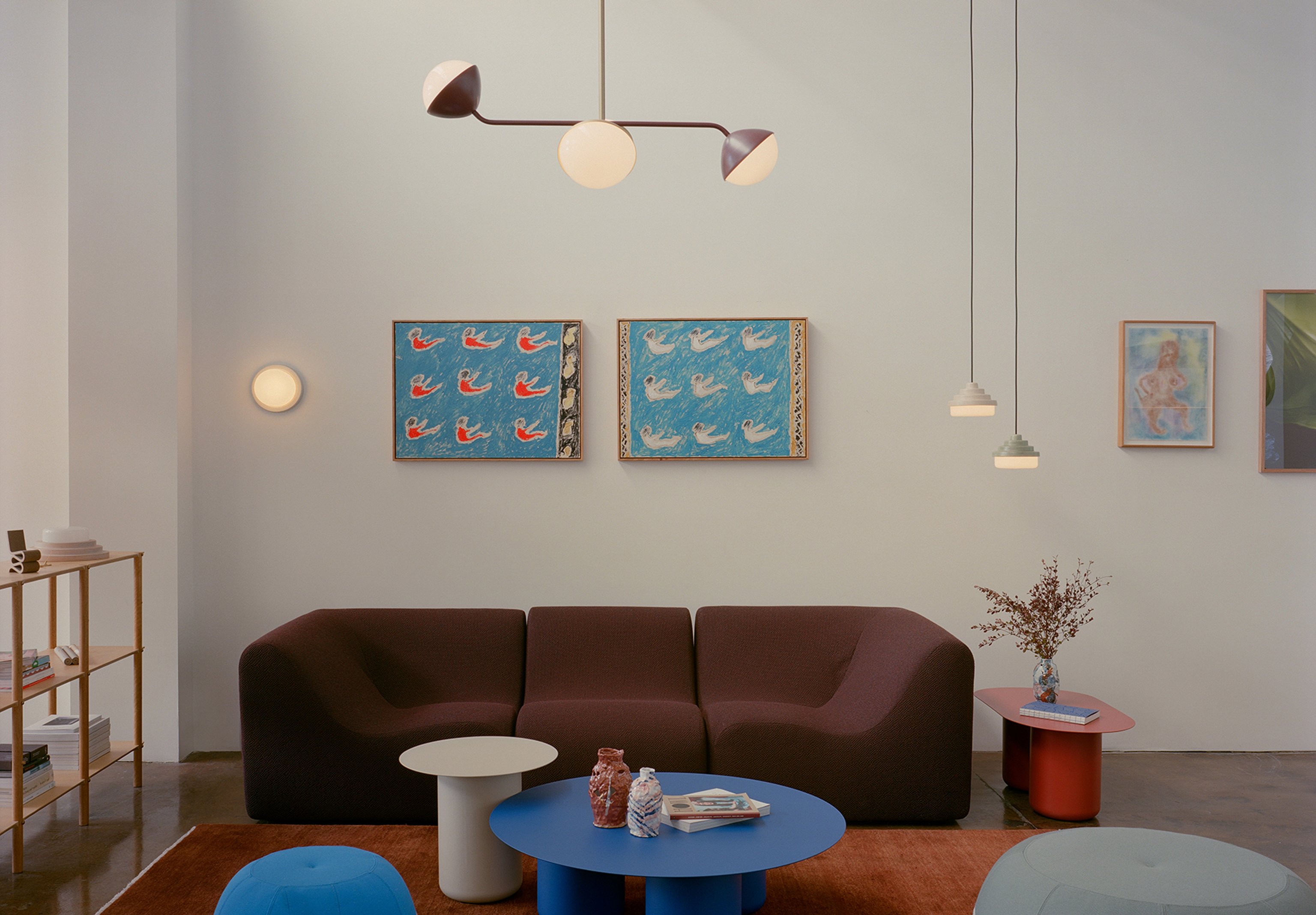 A room with colourful, contemporary furniture and lighting and paintings on the walls