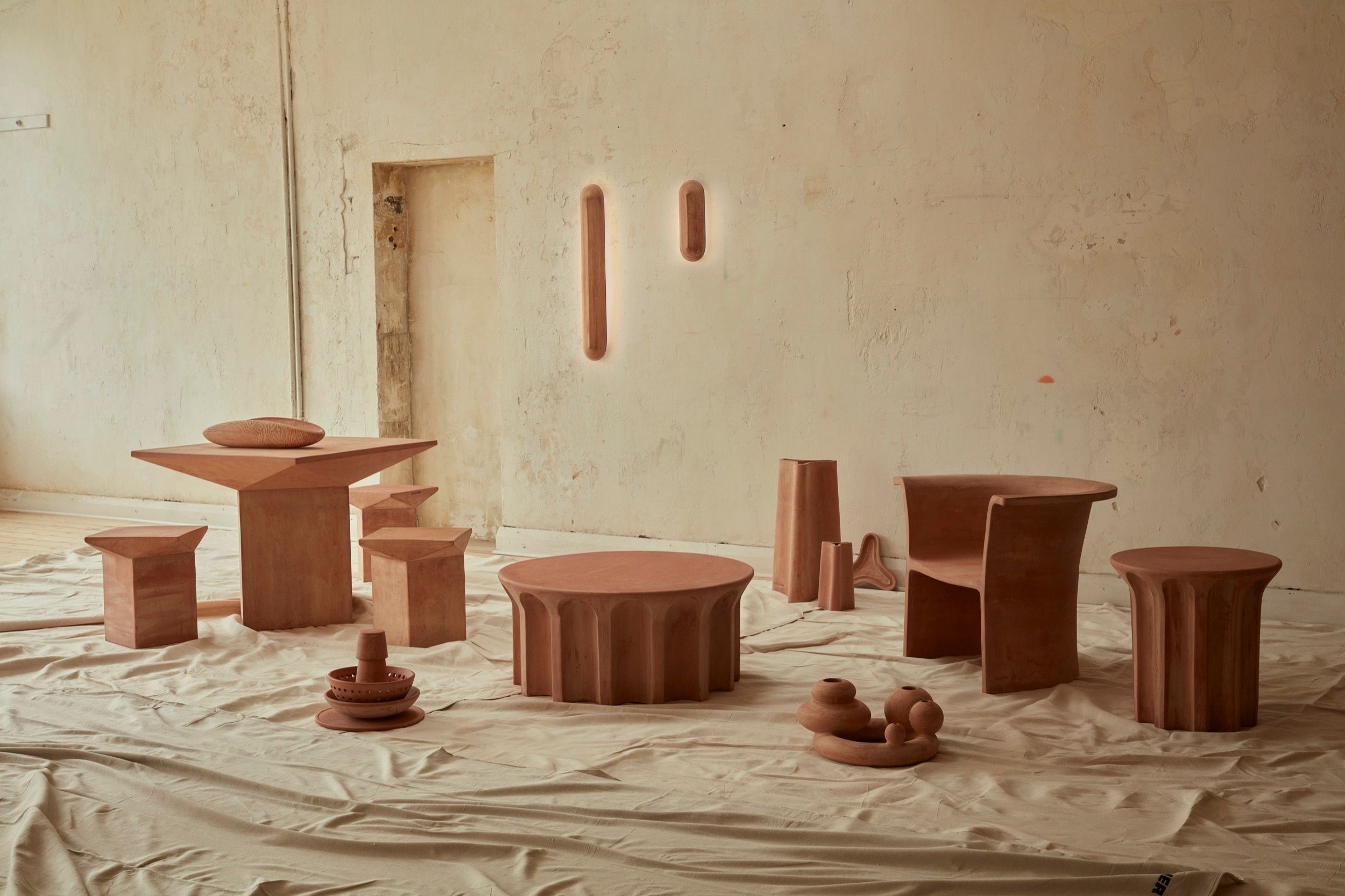 New Volumes collection 02 in a neutral coloured room. A collection of terracotta furniture pieces, lighting and objects
