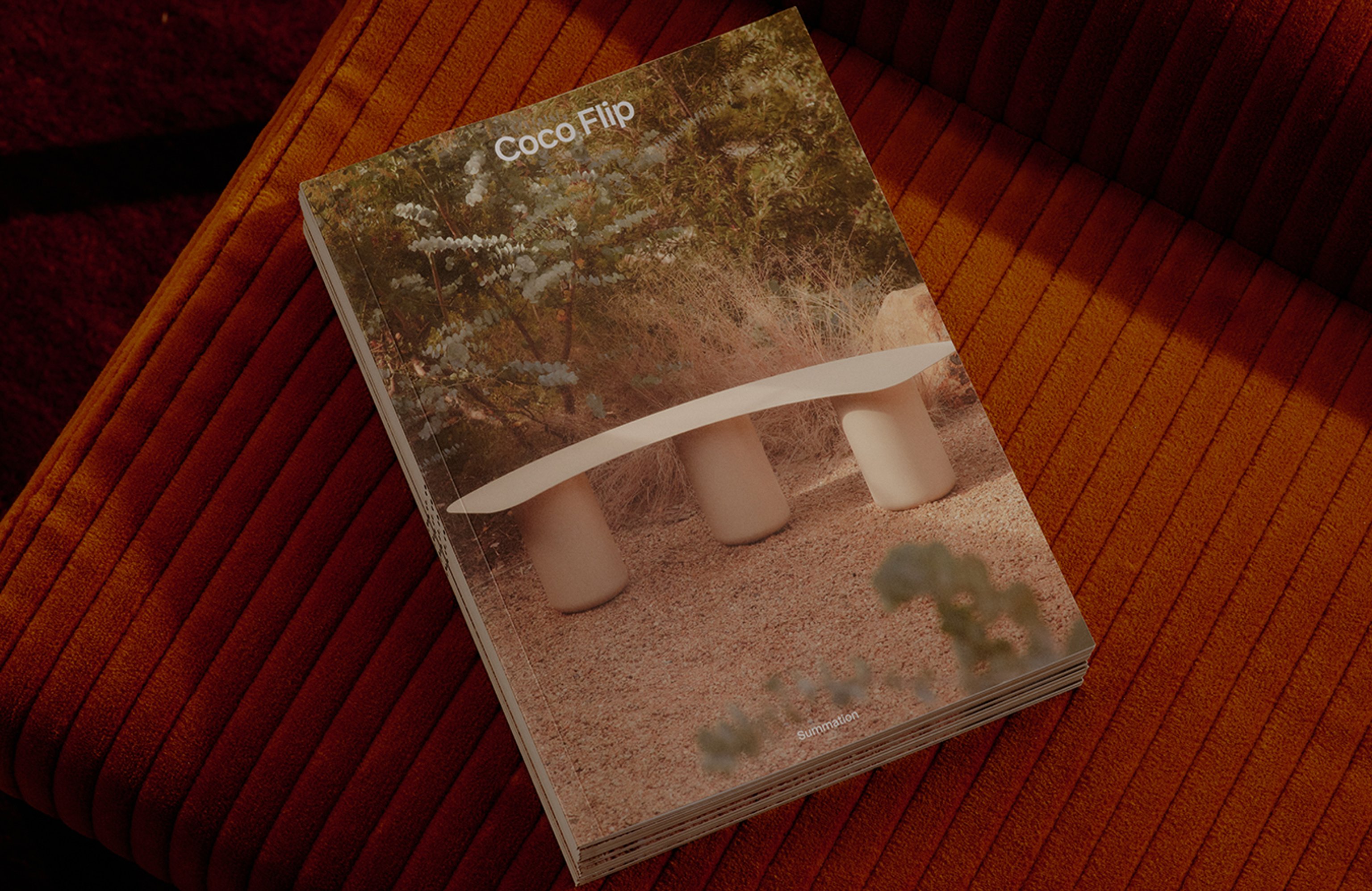 Coco Flip's printed brand booklet 'Summation' sits on a red corduroy bench