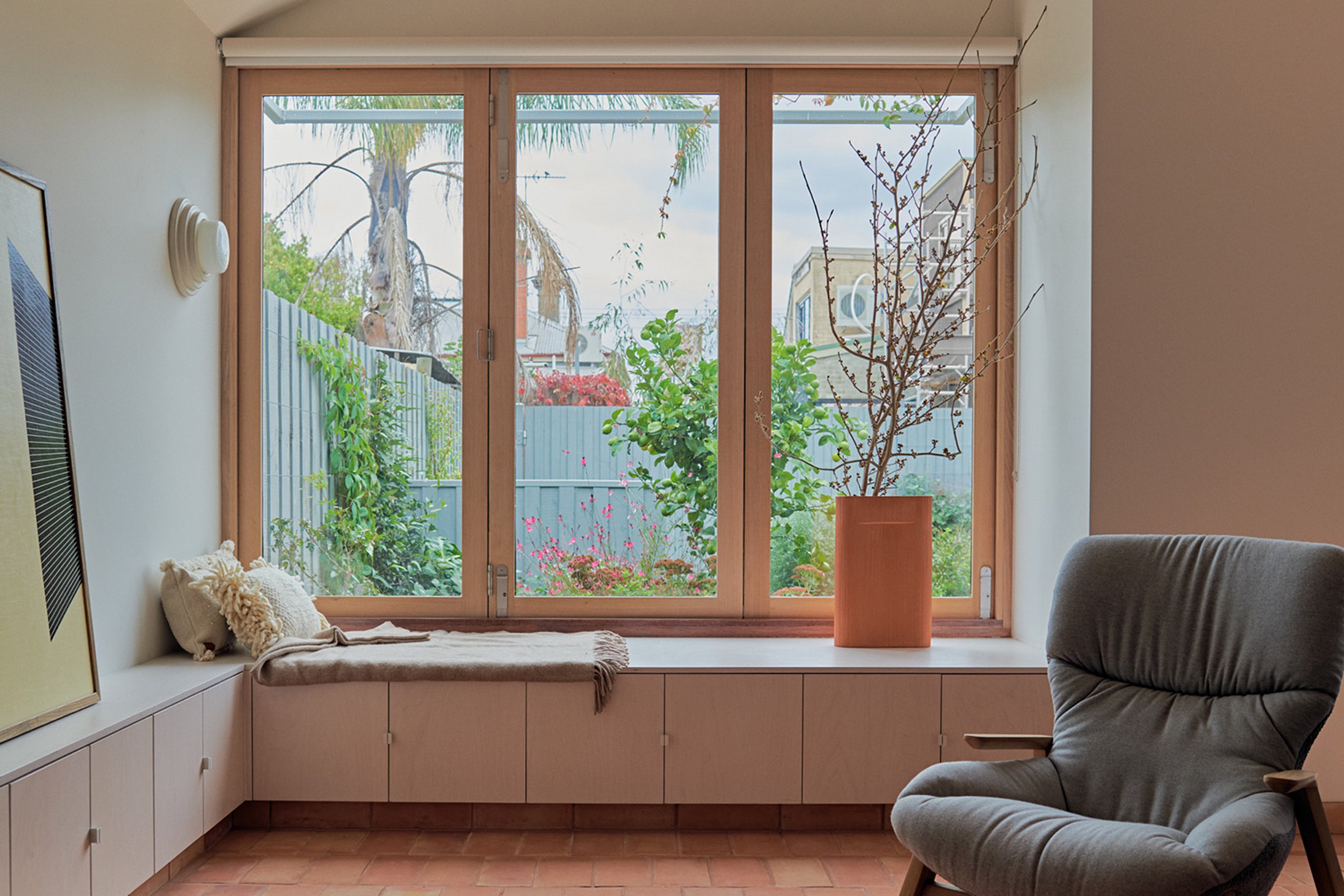 A living room with large timber bi-fold windows, looking out to a landscaped backyard
